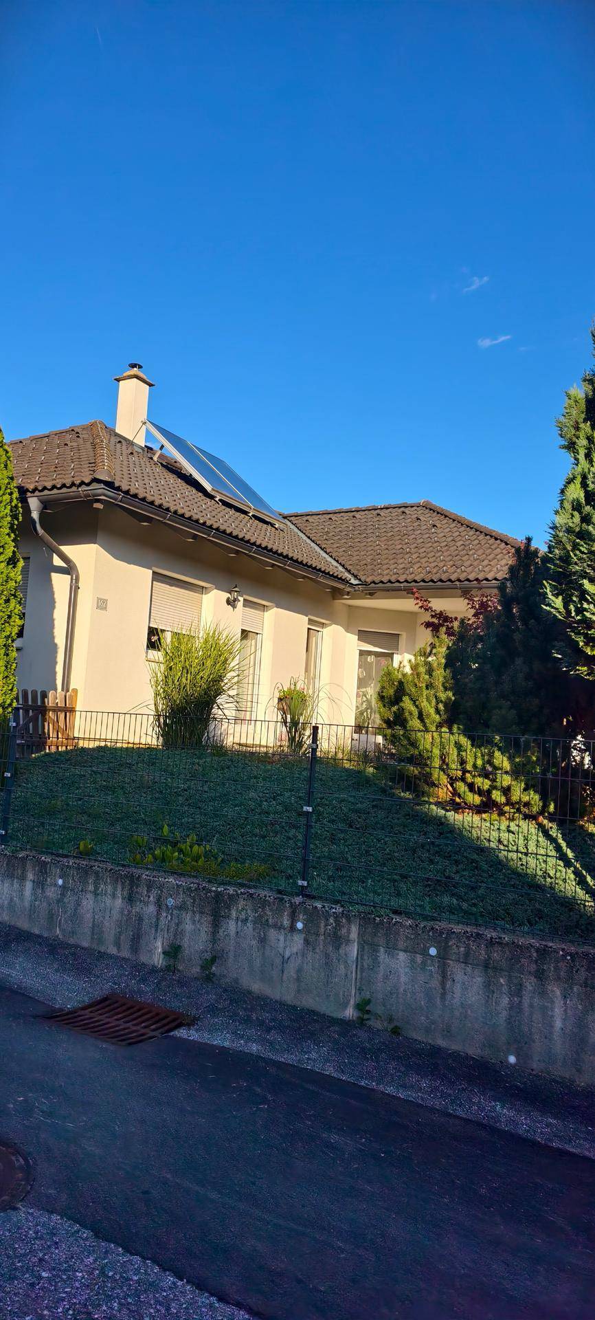 Seitenansicht des Hauses mit Photovoltaikanlage auf dem Dach und gepflegtem Vorgarten.