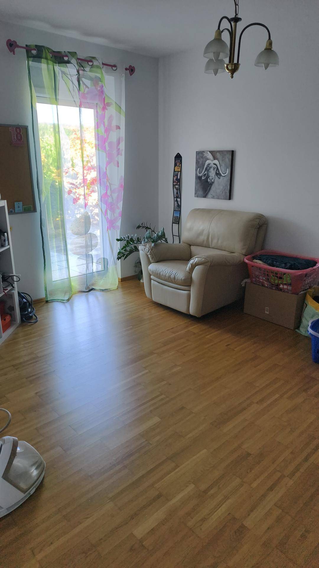 Heller Raum mit Holzboden, einem bequemen Sessel und Zugang zu einem Balkon oder Garten.