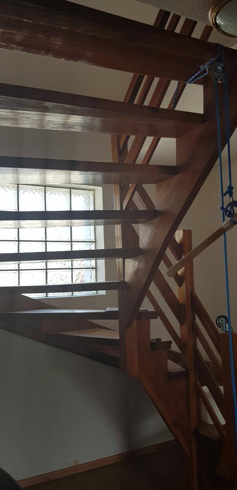 Holztreppe mit Glasbausteinfenster, das den Treppenbereich mit Tageslicht erhellt.