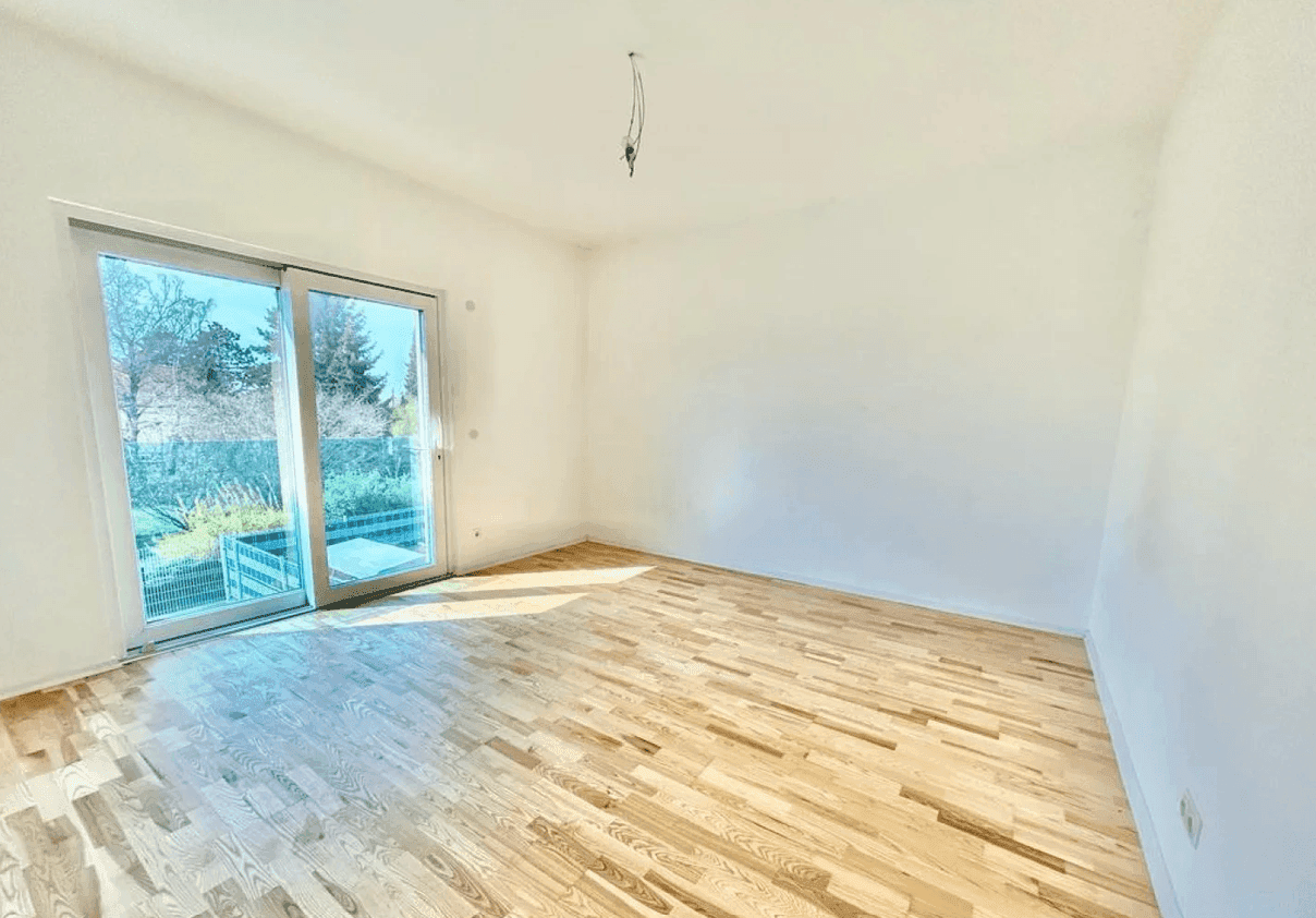 Helles Schlafzimmer mit Parkettboden und großer Schiebetür zum Balkon oder zur Terrasse.
