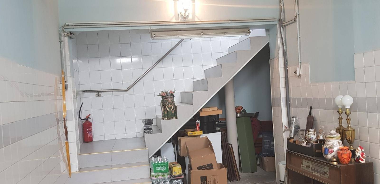 Gefliester Bereich mit einer Treppe und Lagerfläche darunter, möglicherweise ein Abstellraum.