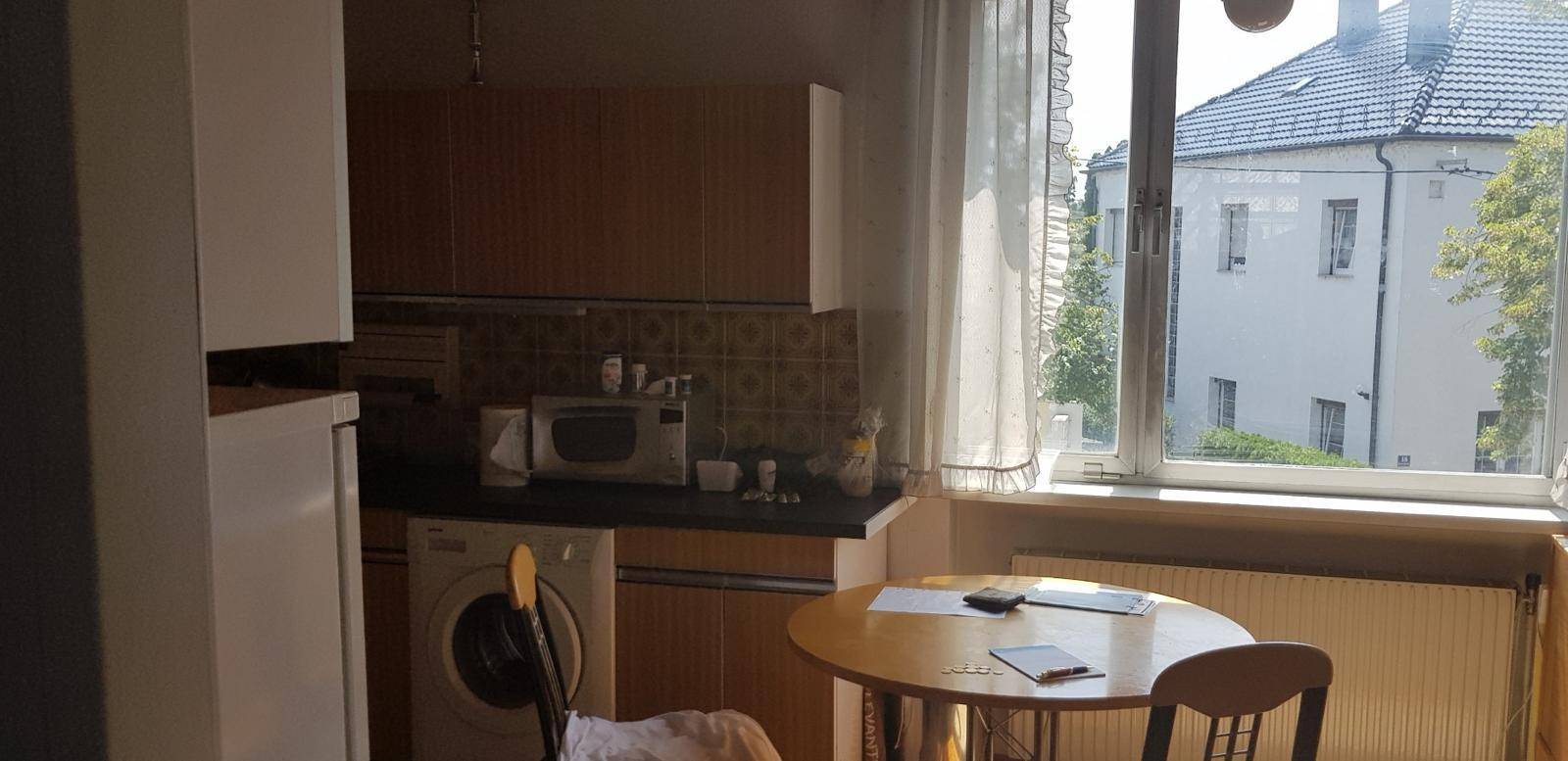 Küche mit kleinem Esstisch, Fenster und integrierter Waschmaschine unter der Arbeitsplatte.