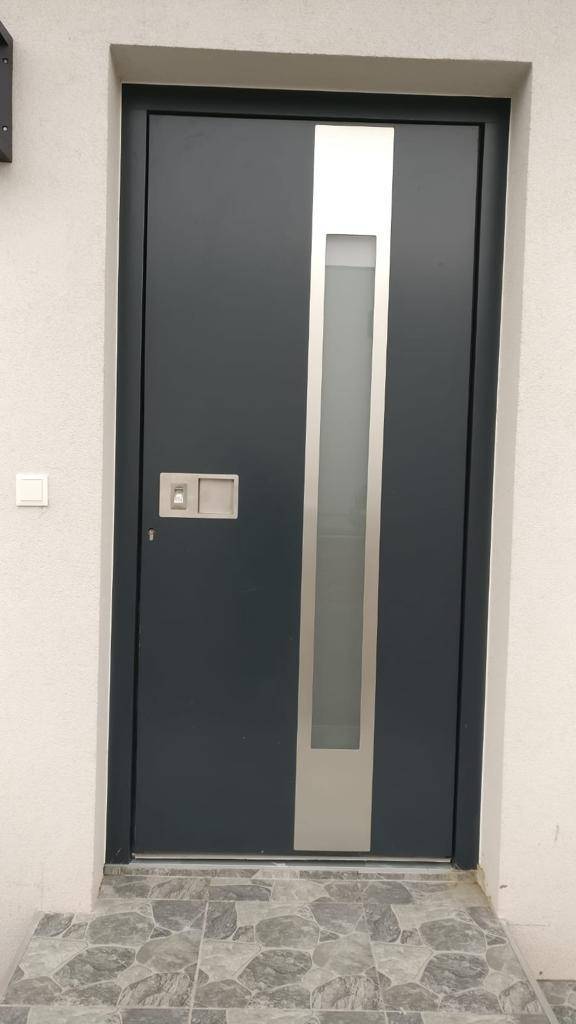 Moderne anthrazitfarbene Eingangstür mit vertikalem Glaseinsatz und elegantem Edelstahlgriff.