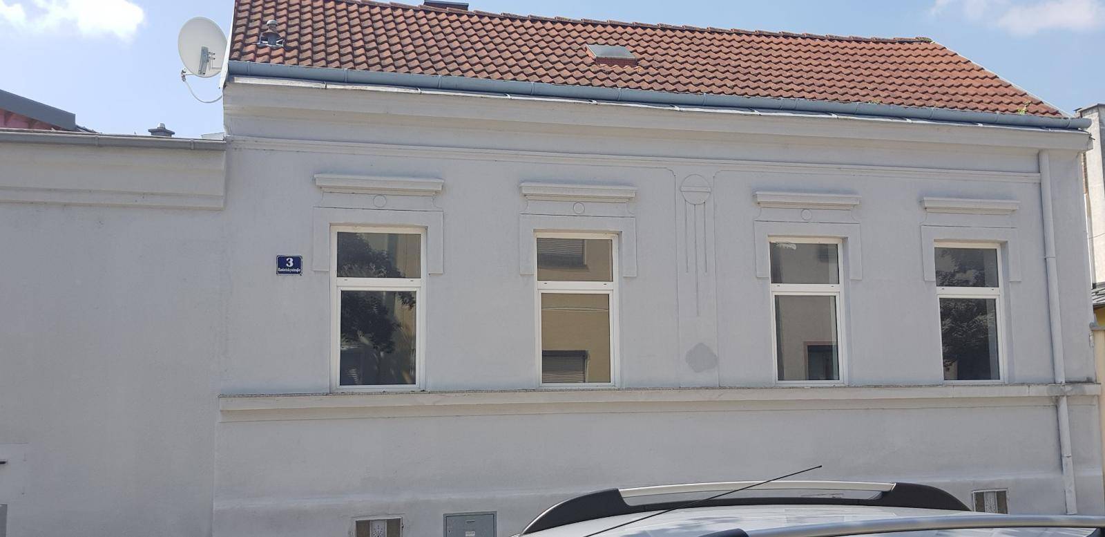 Seitenfassade des Gebäudes mit mehreren Fenstern und einem traditionellen Ziegeldach.
