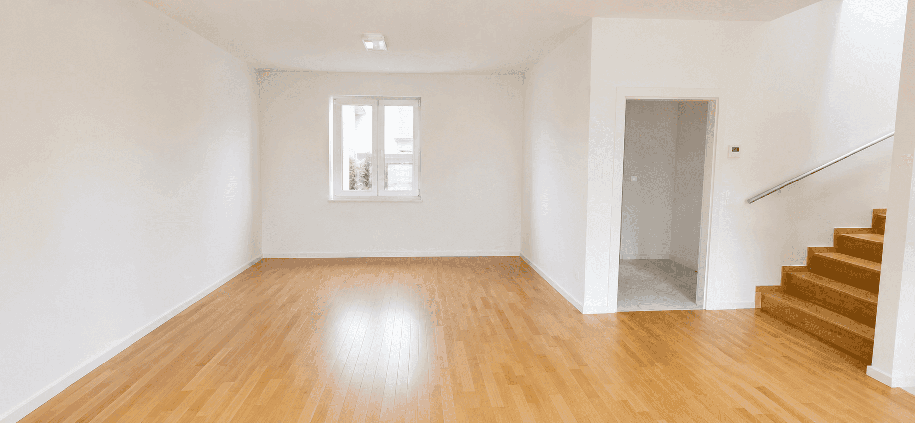 Helles Wohnzimmer mit Parkettboden, großem Fenster und offenem Zugang zur Holztreppe.