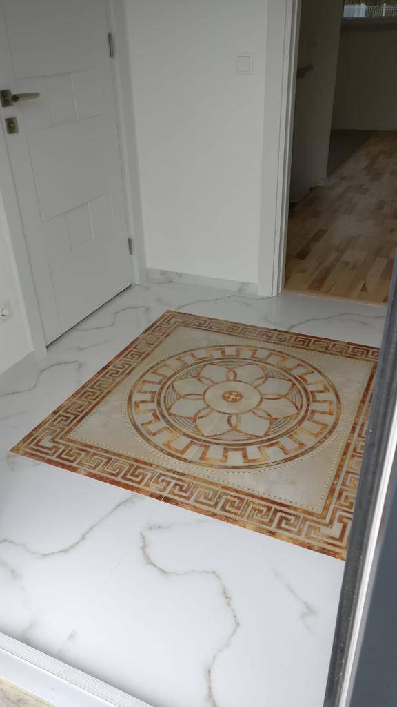 Detailansicht des Fliesenbodens im Eingangsbereich mit ornamentalem Muster und Übergang zu Parkett.