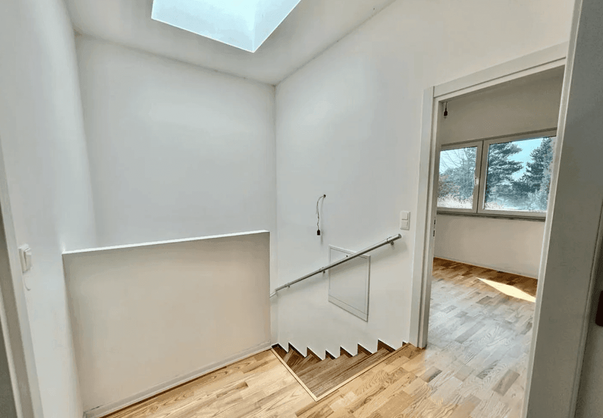 Heller Treppenabsatz mit Holztreppe, Oberlicht und Zugang zu weiteren Räumen im Obergeschoss.