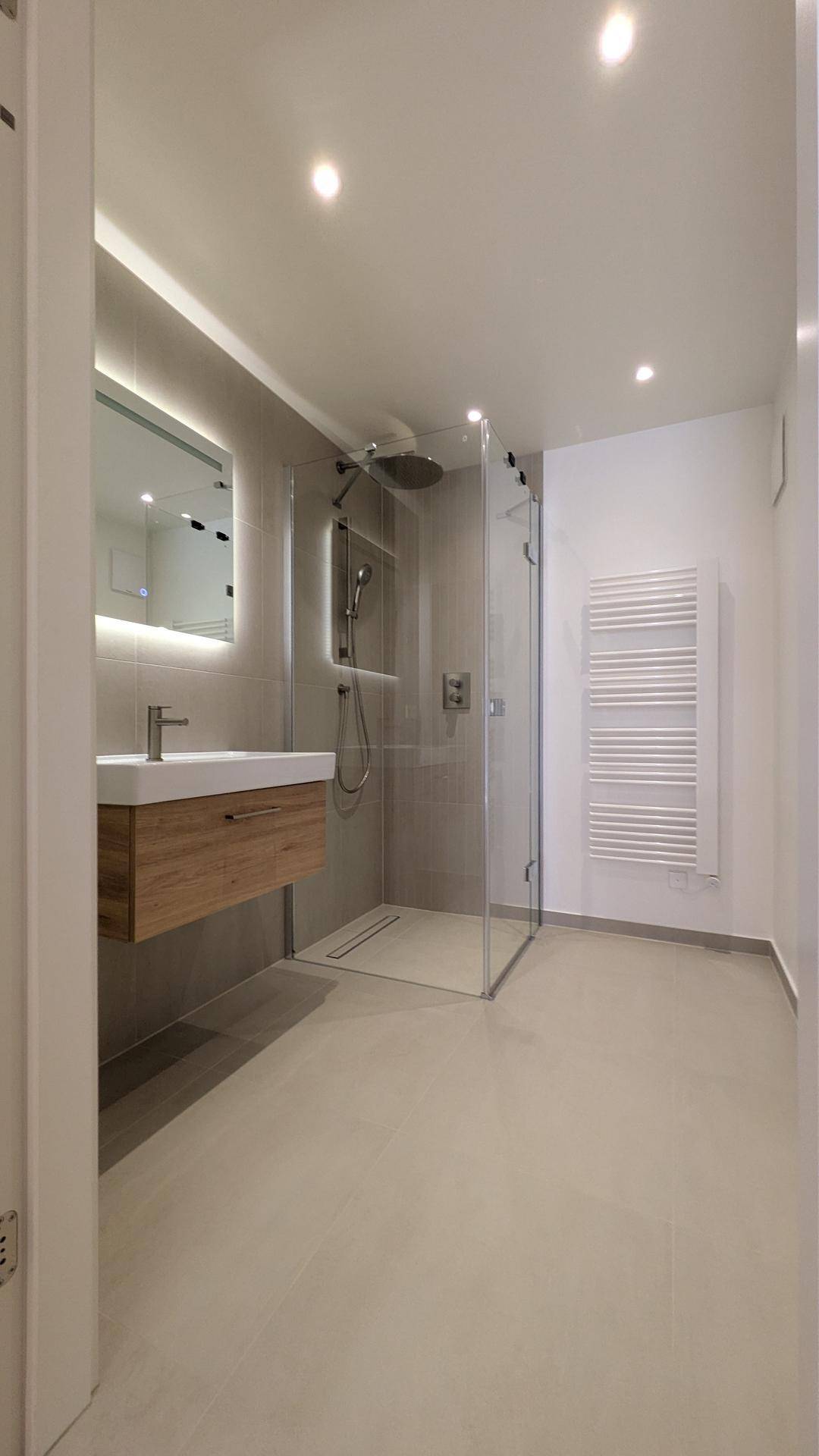 Modernes Badezimmer mit begehbarer Dusche, schwebendem Waschtisch und beheiztem Handtuchhalter.