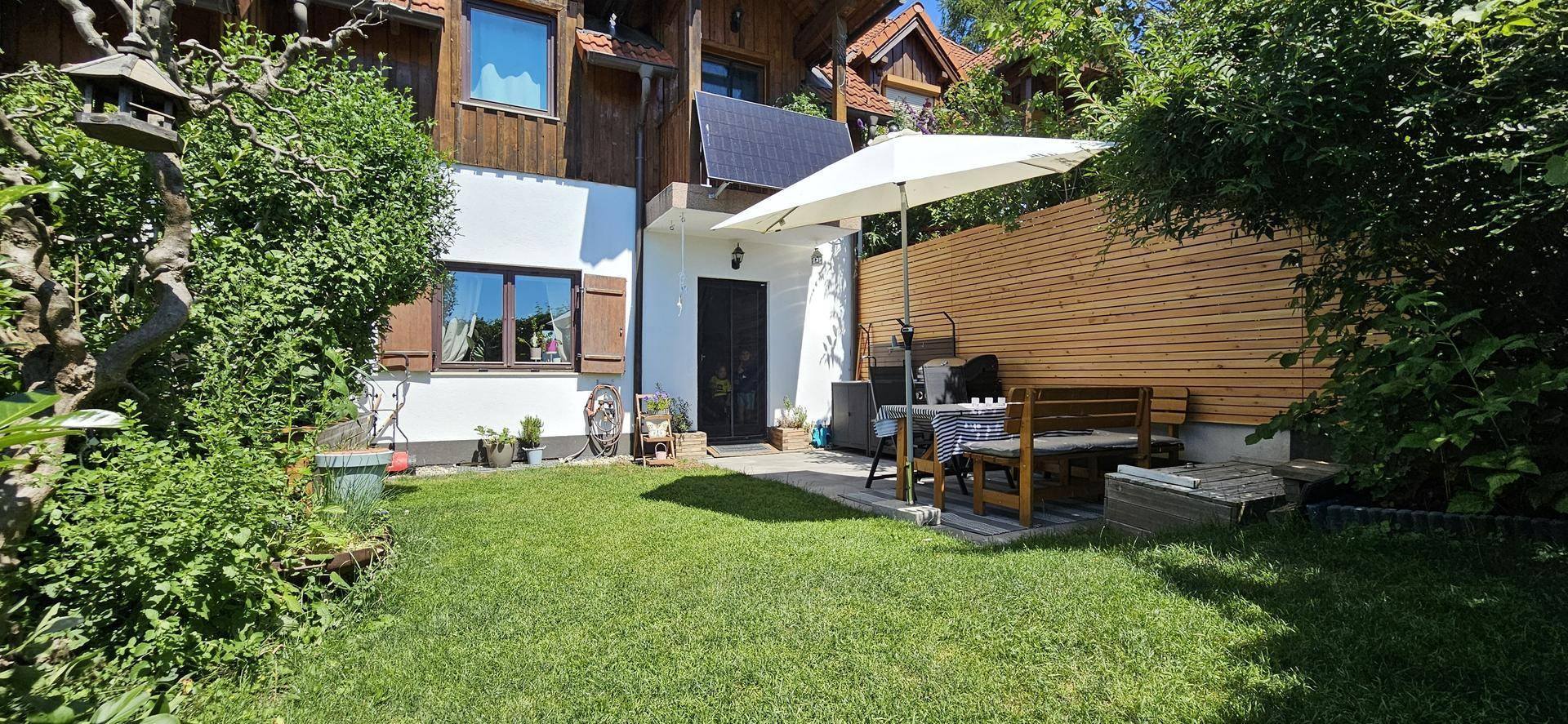 Charmantes Haus mit Gartenbereich, Rasenfläche und einer kleinen Terrasse mit Sitzgelegenheiten.