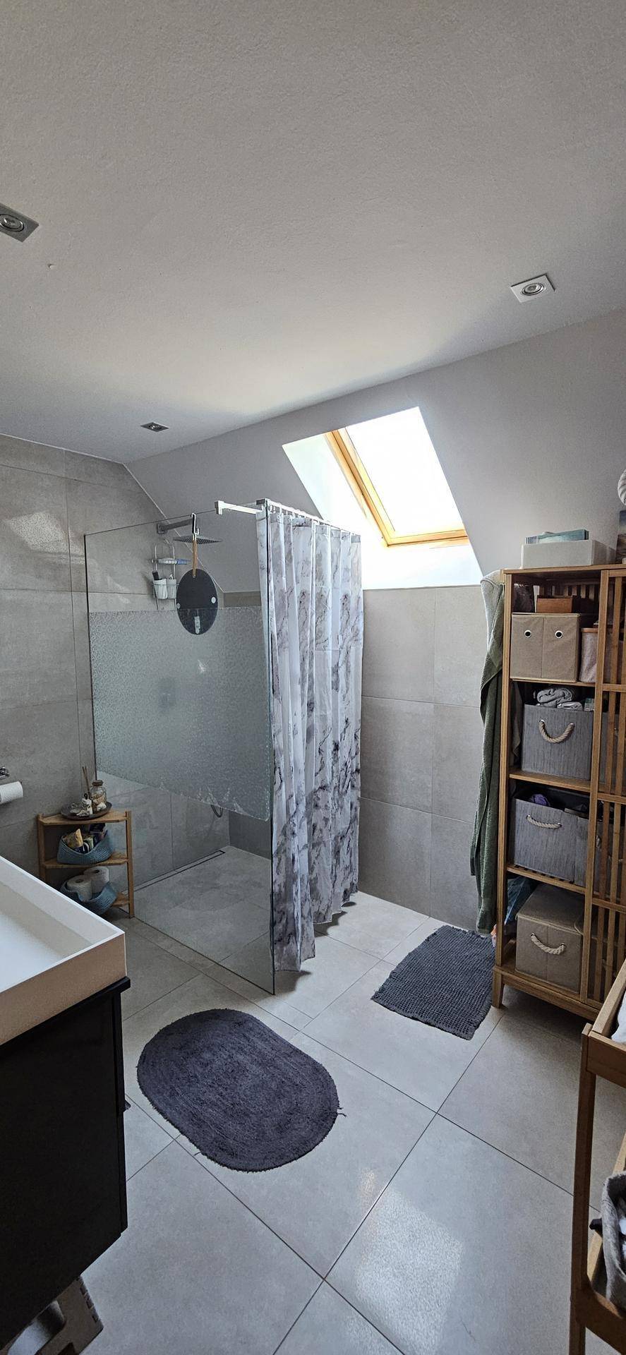 Modernes Badezimmer im Dachgeschoss mit begehbarer Dusche, Fliesenboden und Dachfenster.