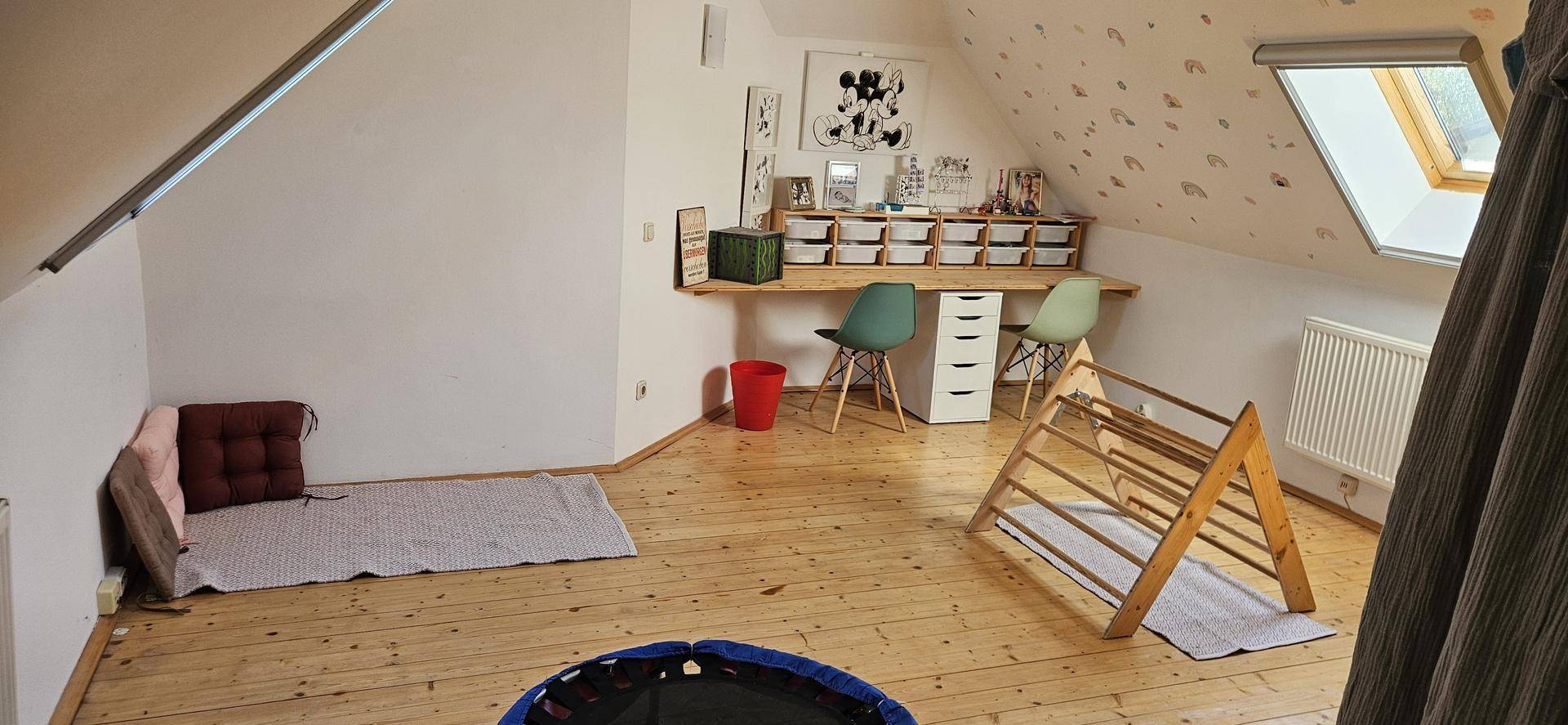 Helles Dachzimmer mit Holzboden, Spielbereich und Dachfenster, ideal als Kinderzimmer nutzbar.