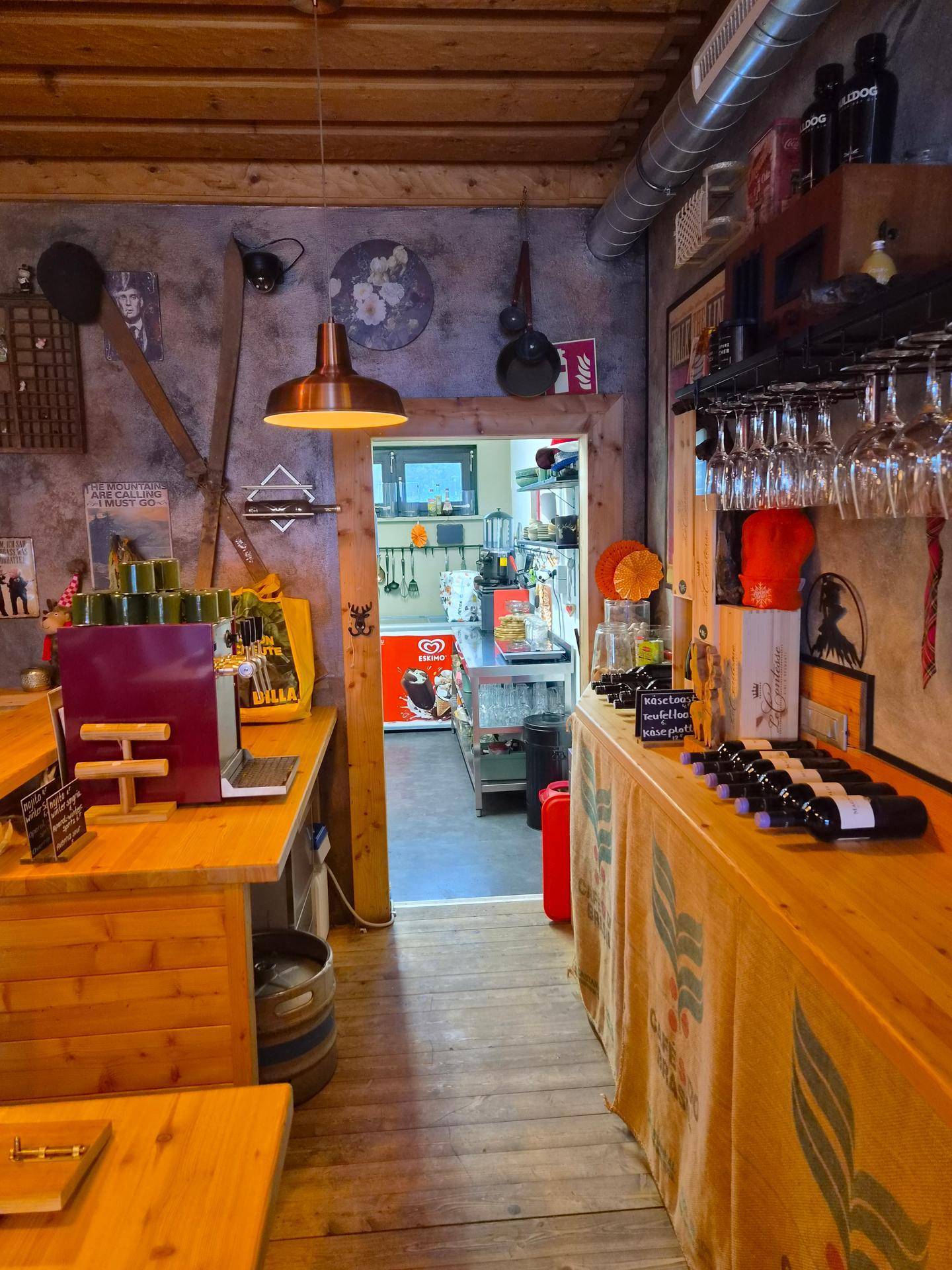 Barbereich mit Holztresen, Zapfanlage und Durchgang zur Küche im Hintergrund.