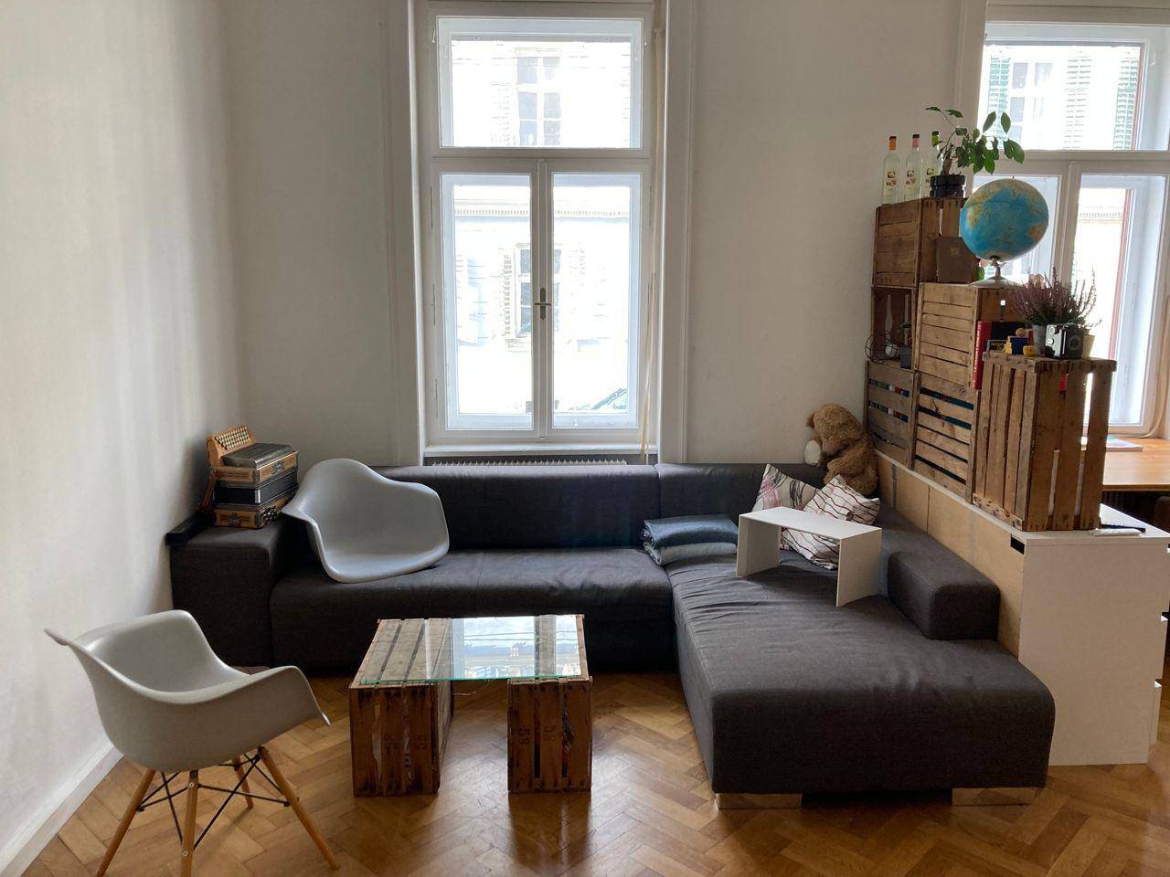Geräumiges Wohnzimmer mit großem Ecksofa, Couchtisch und hohen Fenstern für viel Tageslicht.