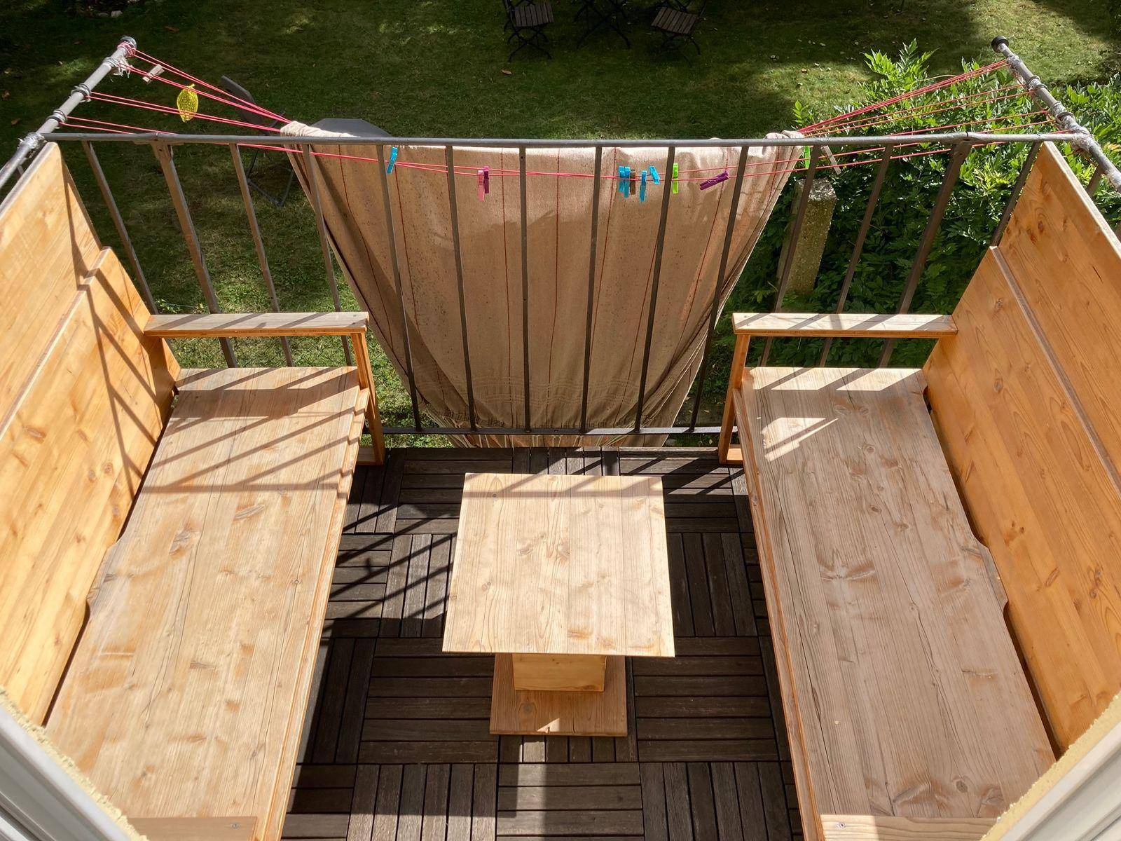 Kleiner Balkon mit Holzbänken und Tisch, ideal für eine gemütliche Auszeit im Freien.