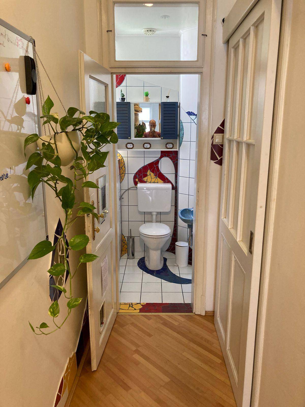 Separates WC mit Toilette und farbenfrohen Fliesen, die einen einzigartigen Stil verleihen.
