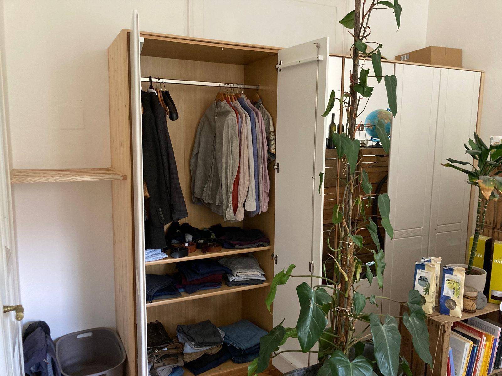 Offener Kleiderschrank mit Kleiderstange und Regalen für Kleidung in einem Schlafzimmer.