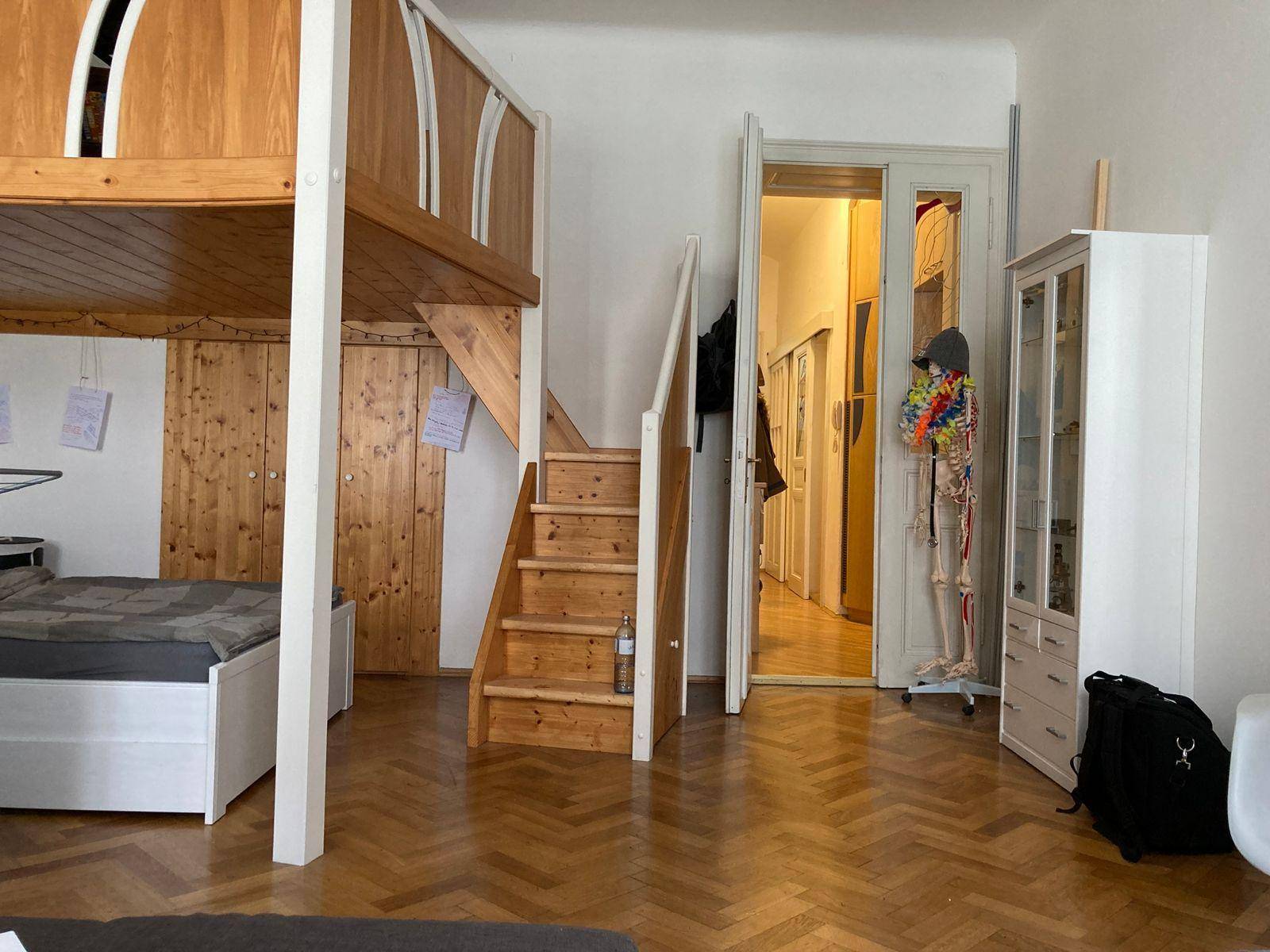 Schlafzimmer mit Hochbett und Holztreppe, die zu einer oberen Ebene führt, mit Blick in den Flur.