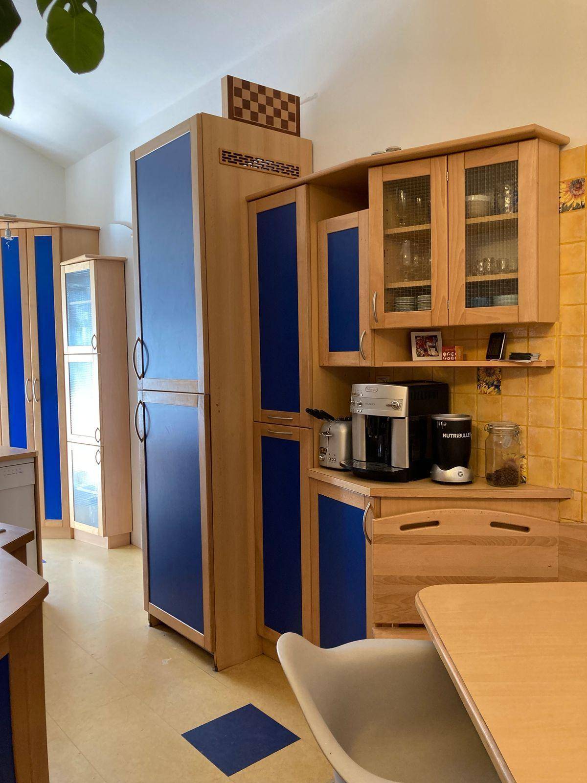 Küche mit Holzschränken, blauen Akzenten und einem Essbereich, der zum Verweilen einlädt.
