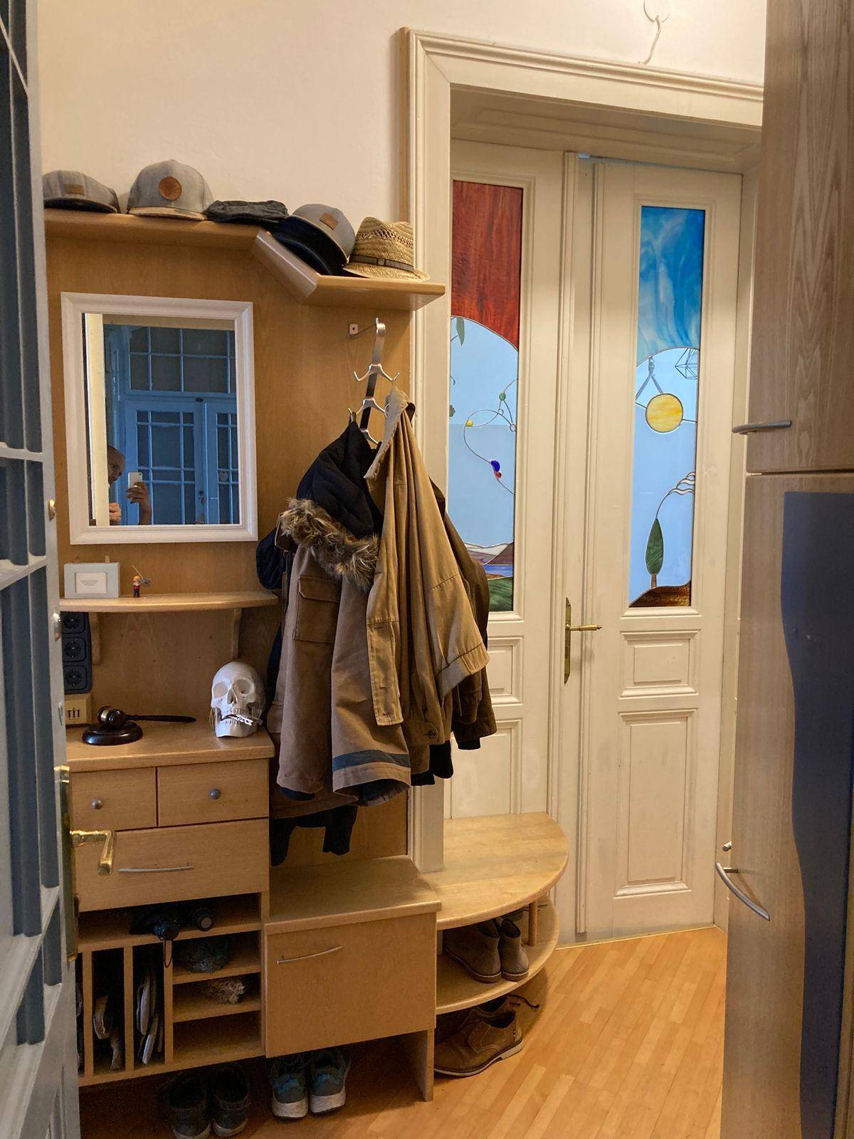 Eingangsbereich mit Garderobe, Spiegel und dekorativer Tür mit Buntglas, die zum Wohnbereich führt.