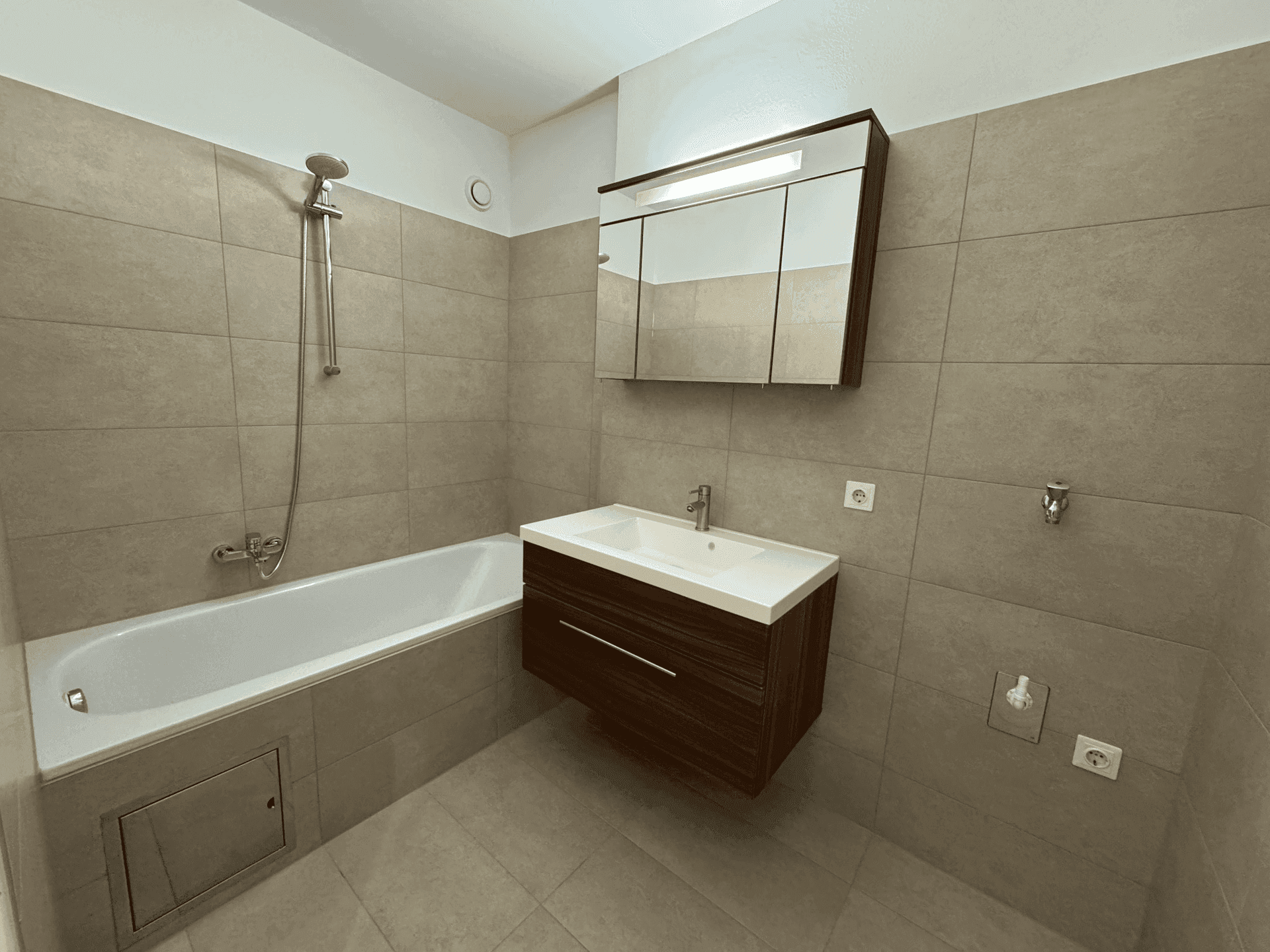 Funktionales Badezimmer mit Badewanne, modernem Waschtisch und Wandfliesen.