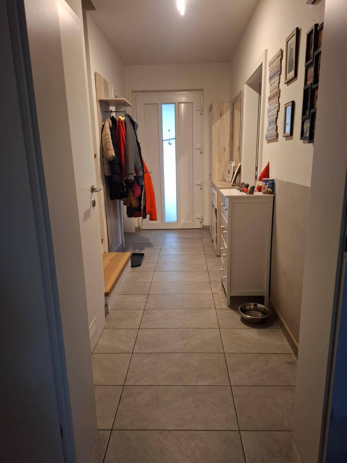 Geräumiger Eingangsbereich mit Fliesenboden, Garderobe und Kommode für zusätzlichen Stauraum.