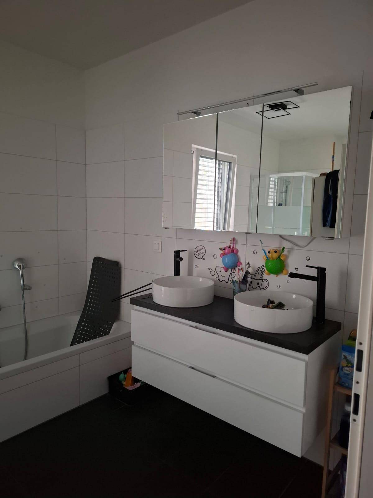 Modernes Badezimmer mit Doppelwaschbecken, Spiegelschrank und Badewanne.