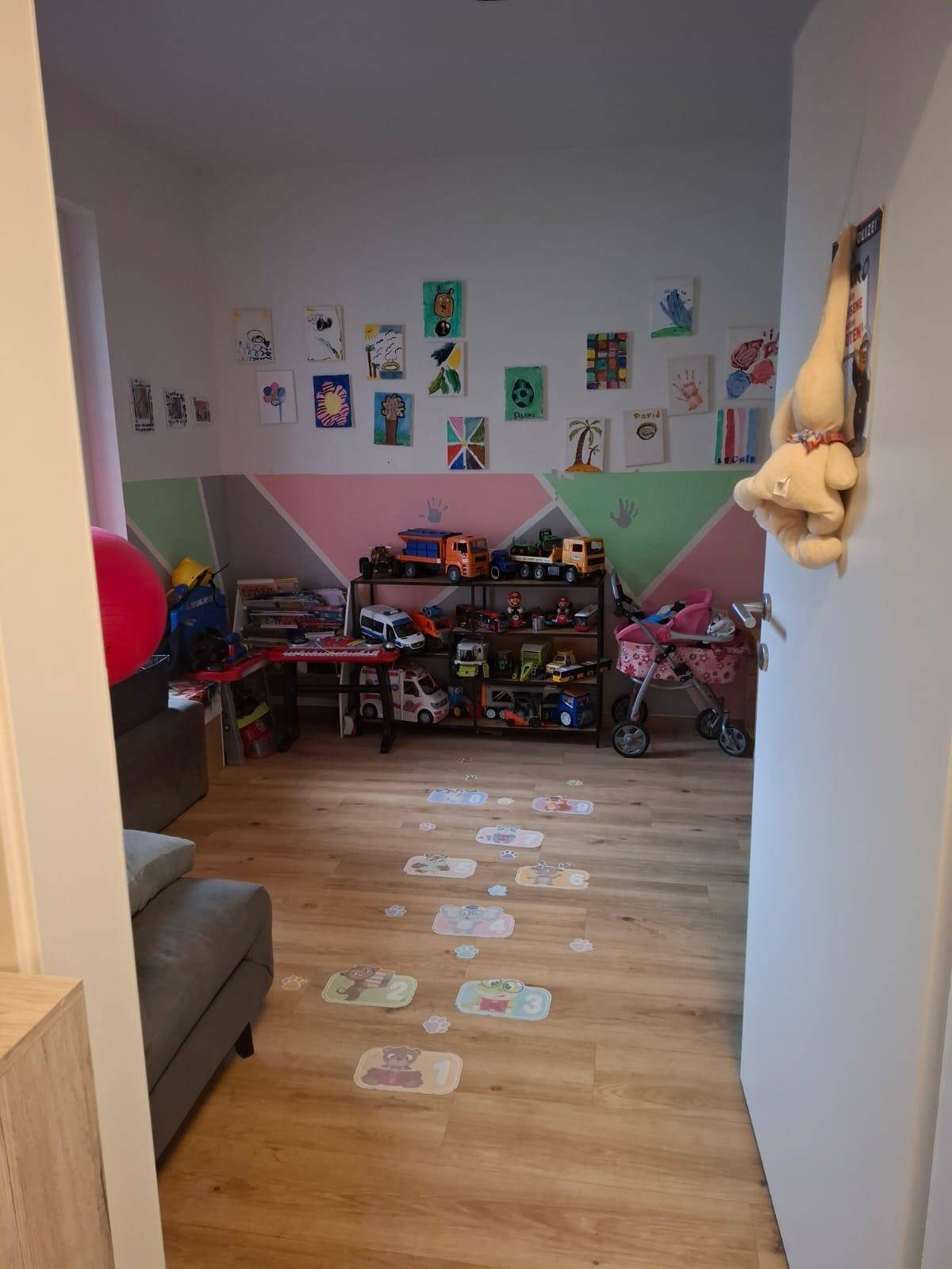 Helles Kinderzimmer mit Spielzeug, Stauraum und farbenfrohen Wanddekorationen für eine spielerische Atmosphäre.