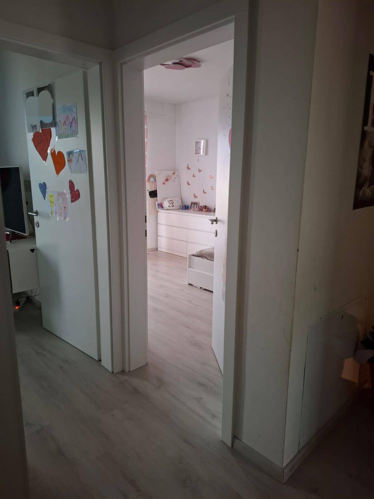 Heller Flur mit Laminatboden, der den Blick in ein liebevoll dekoriertes Kinderzimmer freigibt.