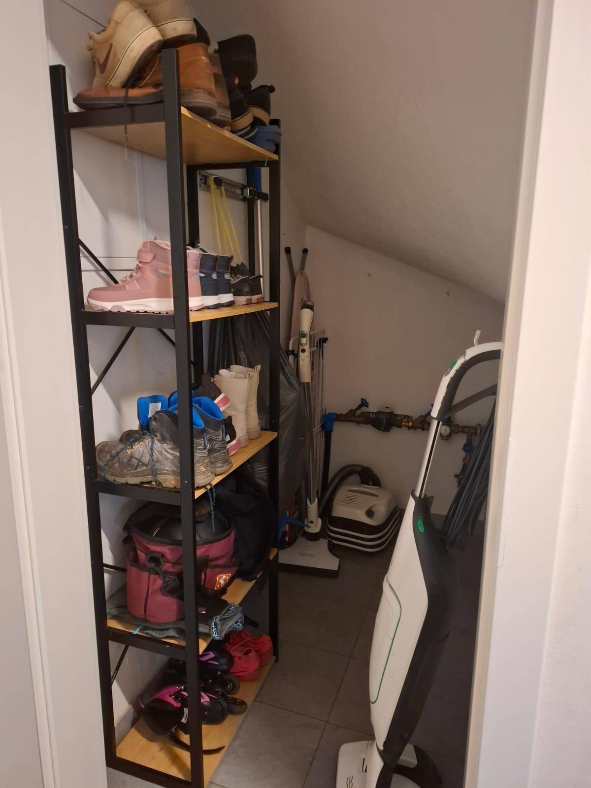 Praktischer Abstellraum unter der Dachschräge mit Regalen für Schuhe und Haushaltsgeräte.
