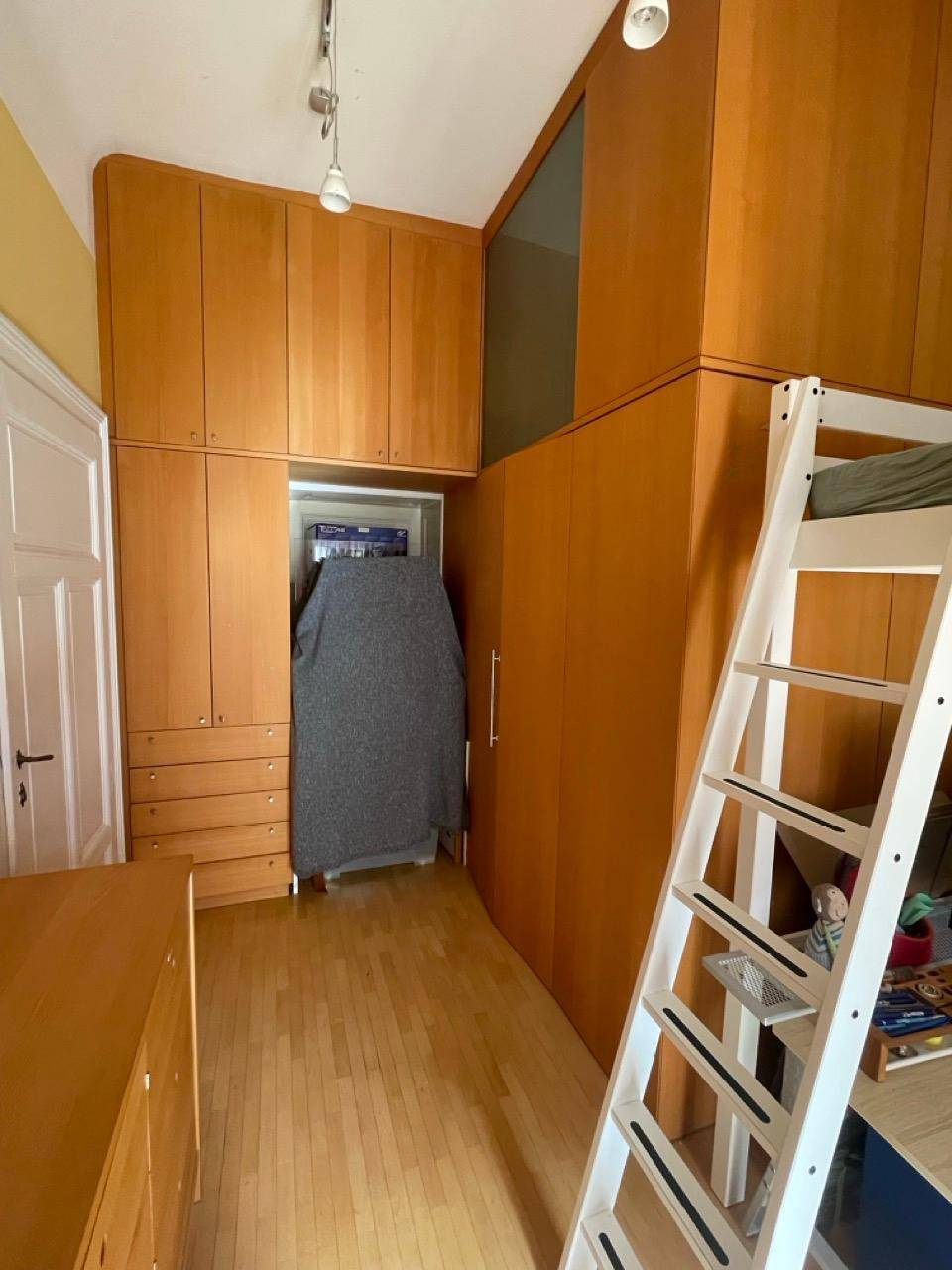 Kinderzimmer mit Einbauschränken, Hochbett und Parkettboden, praktisch und hell.