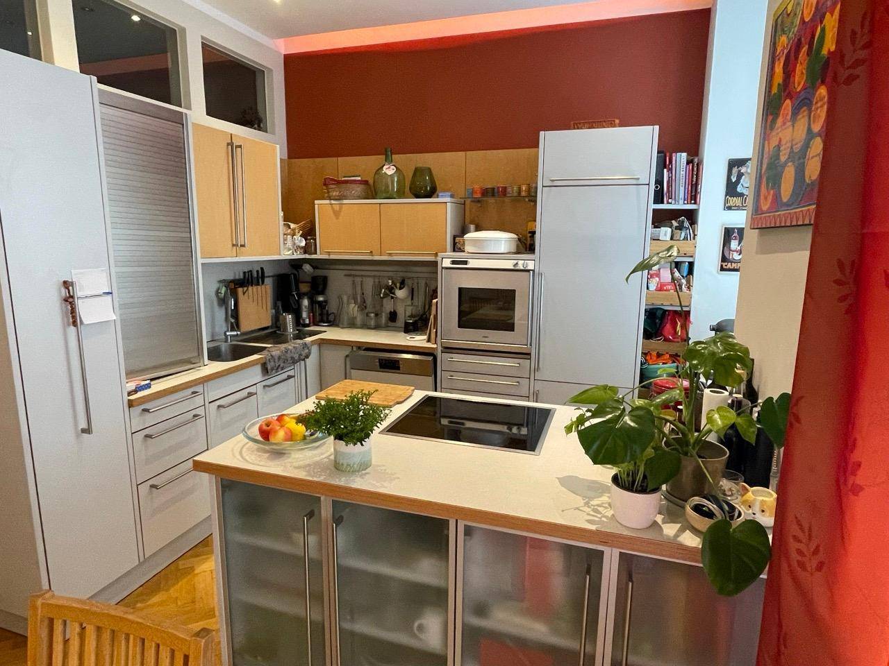 Moderne Einbauküche mit Kochinsel, integrierten Geräten und viel Stauraum.