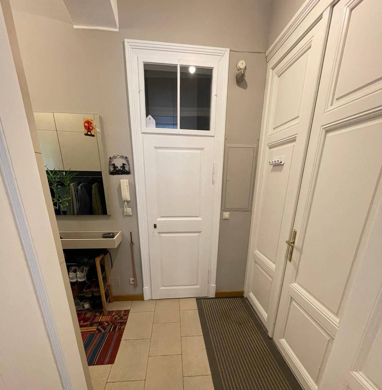 Eingangsbereich mit weißer Tür, Fliesenboden und Garderobe, hell und einladend.