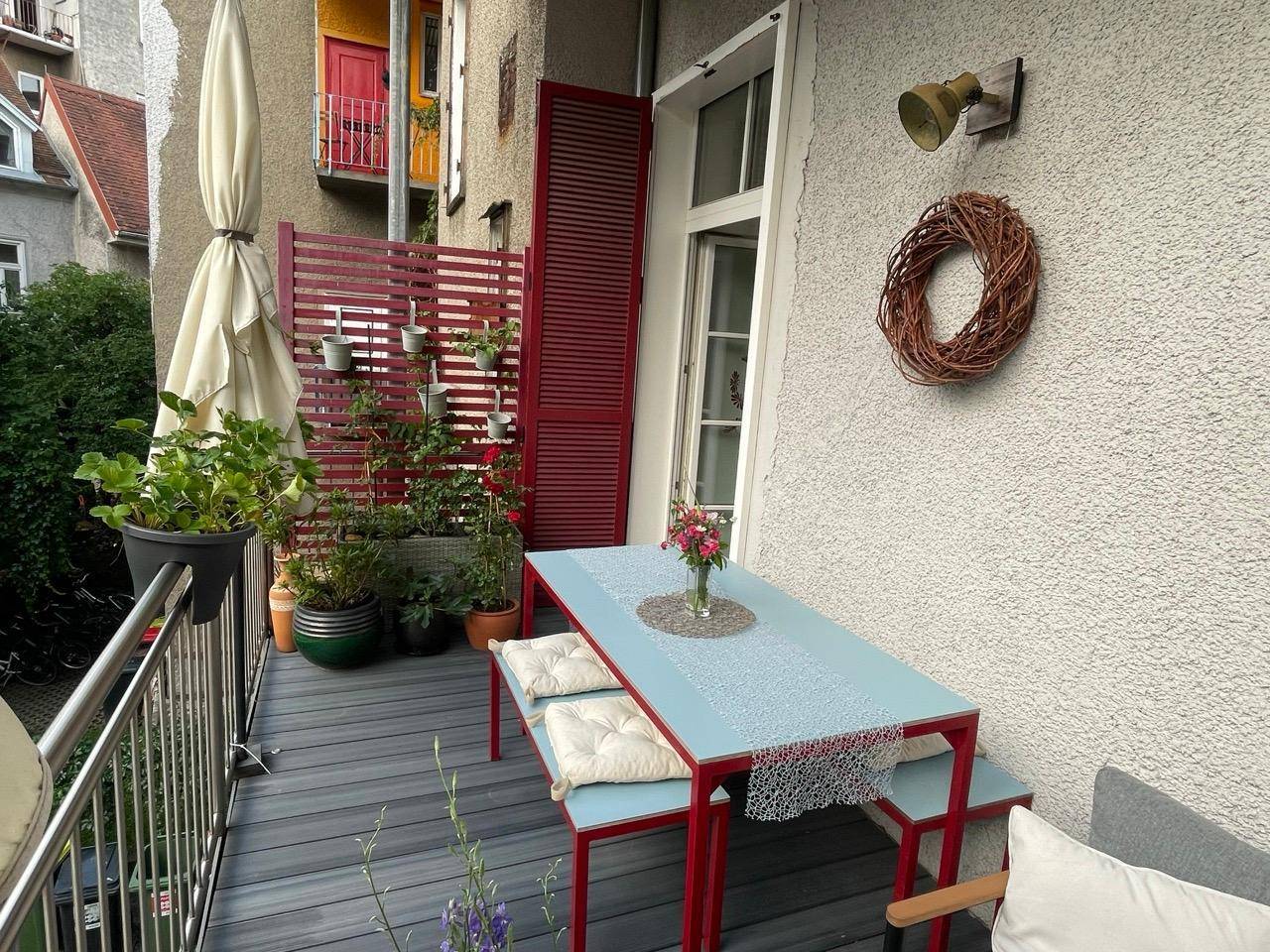 Gemütlicher Balkon mit Sitzgelegenheiten, Pflanzen und Sonnenschirm, ideal zum Entspannen.