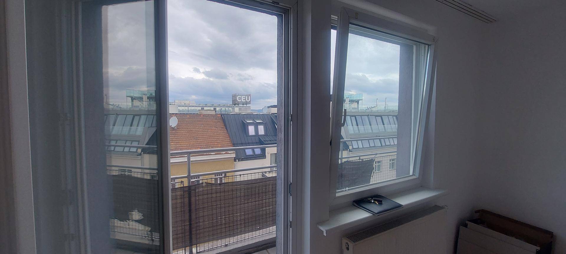 Blick von einem Balkon auf die Dächer der Stadt und umliegende Gebäude.