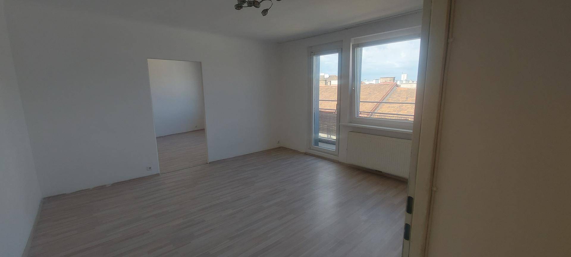 Heller, leerer Raum mit Laminatboden und großen Fenstern, bereit zur individuellen Gestaltung.