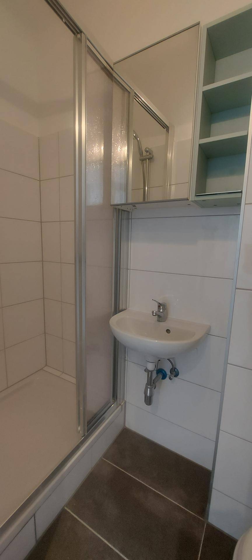 Modernes Badezimmer mit Duschkabine, Waschbecken und Spiegelschrank.