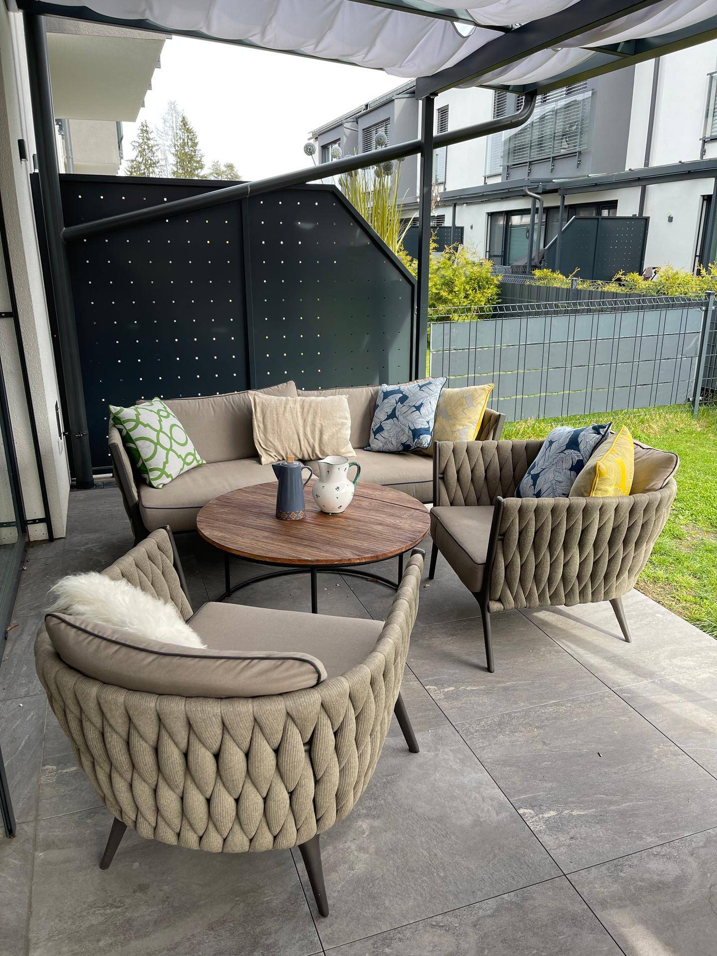 Gemütliche Lounge-Ecke auf der überdachten Terrasse mit bequemen Sitzmöbeln und Kissen.