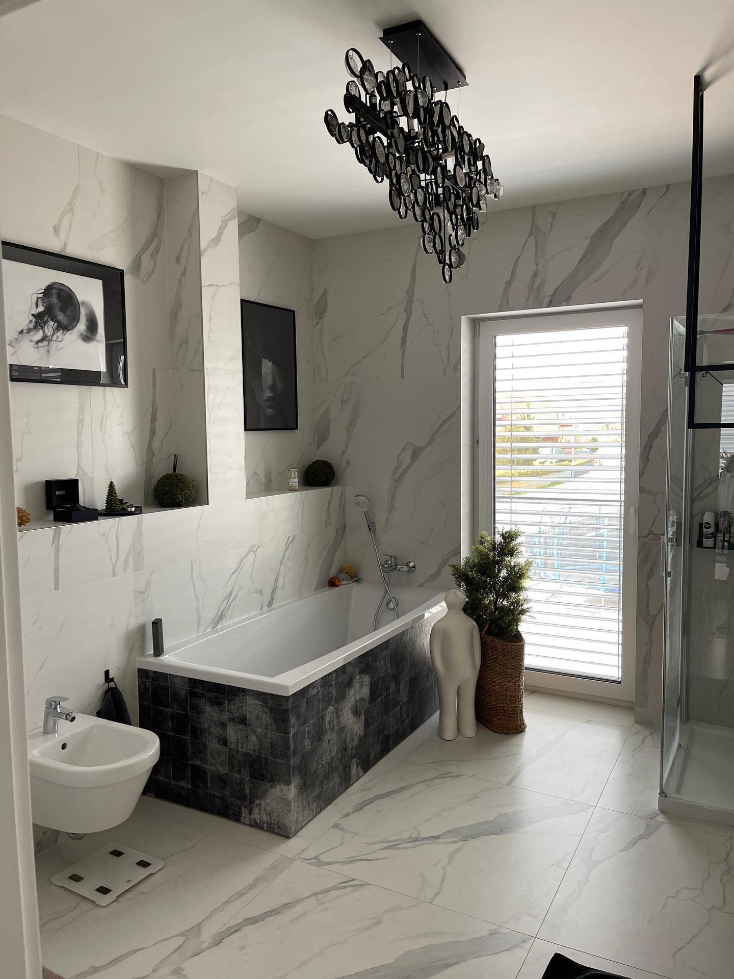 Helles Badezimmer mit Badewanne, Dusche, Bidet und Fenster für Tageslicht.