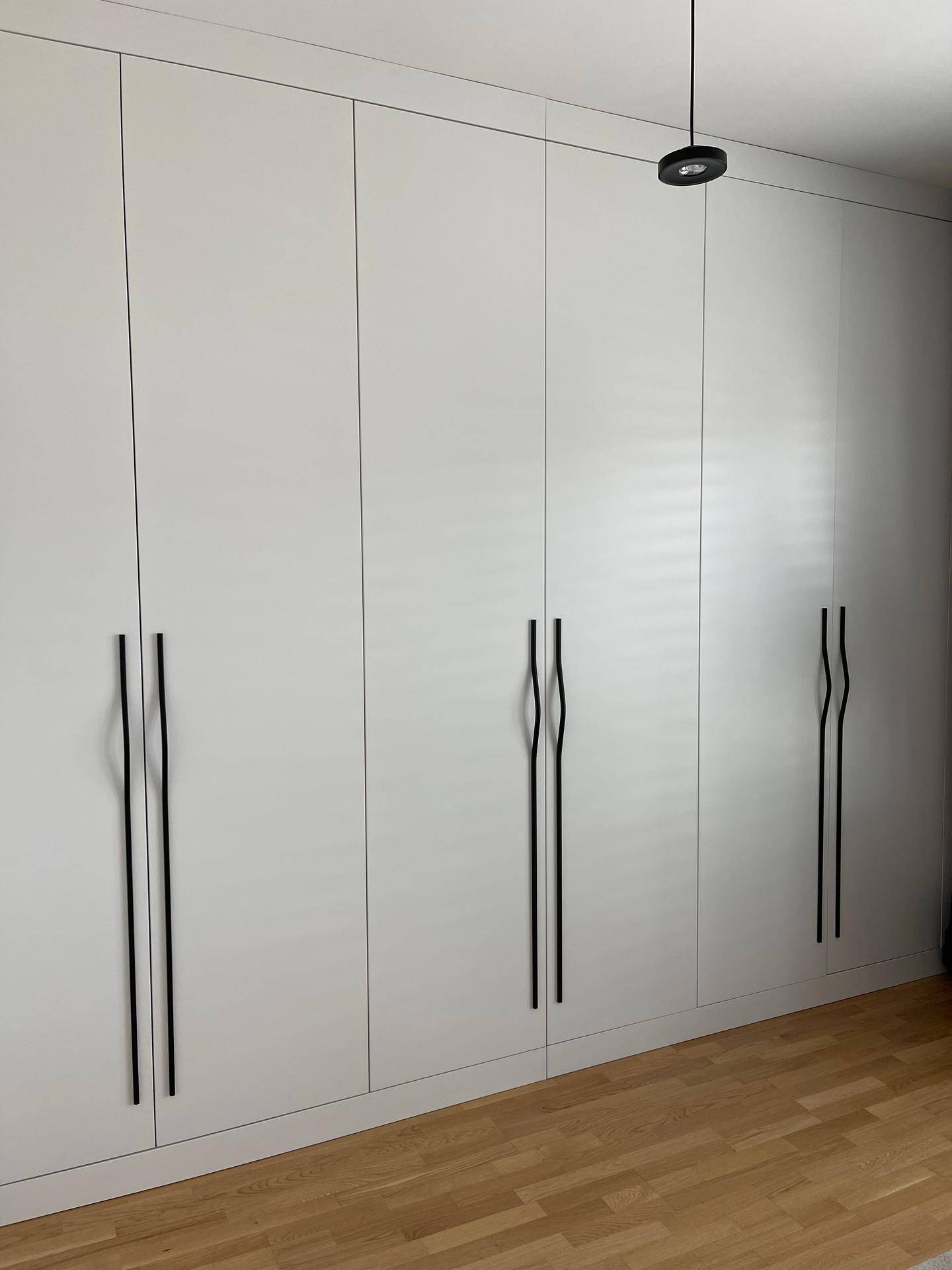 Moderne Einbauschränke mit minimalistischen Griffen und hellem Holzfußboden.