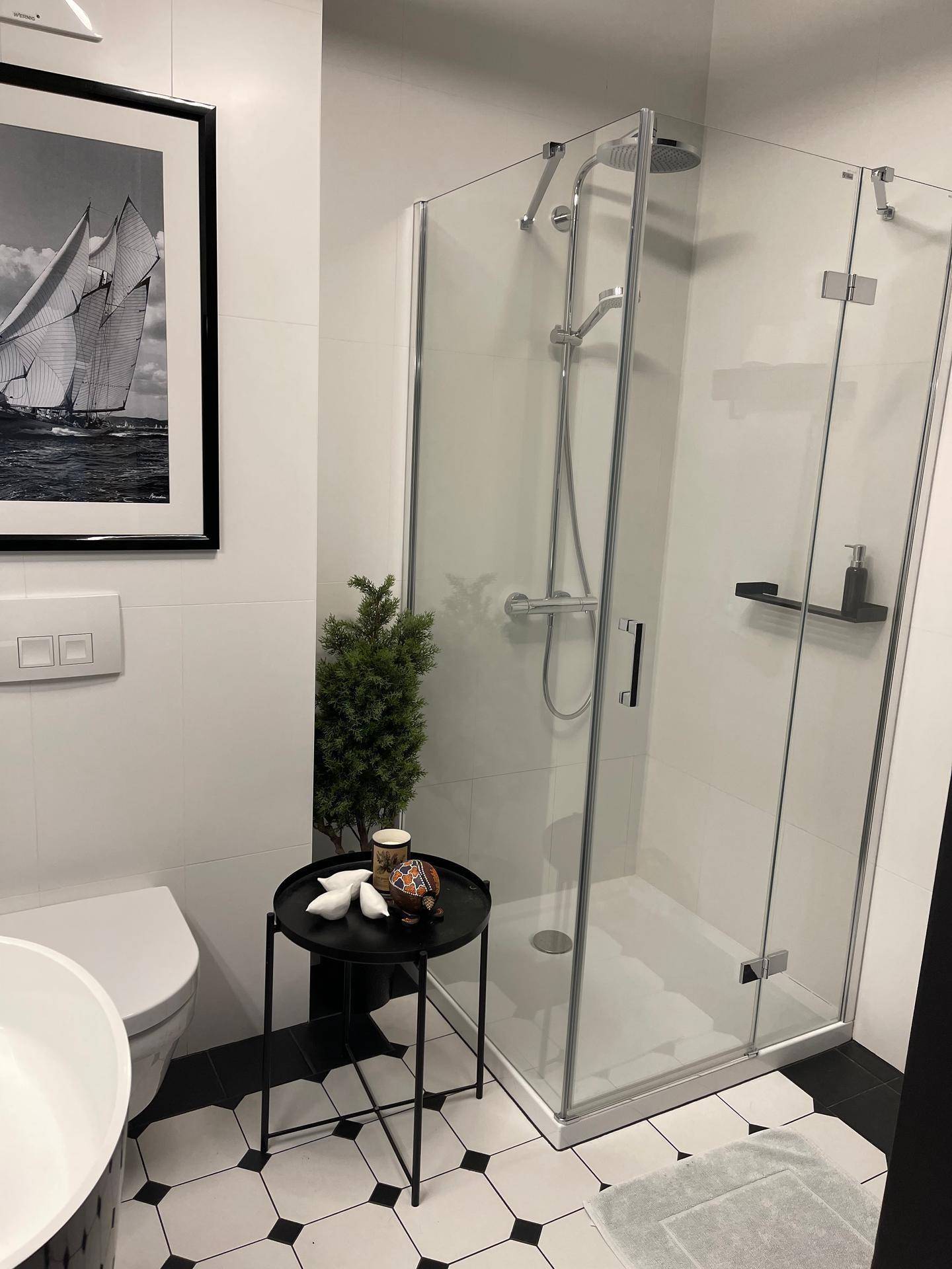 Modernes Badezimmer mit Duschkabine, WC und schwarz-weißem Fliesenboden.