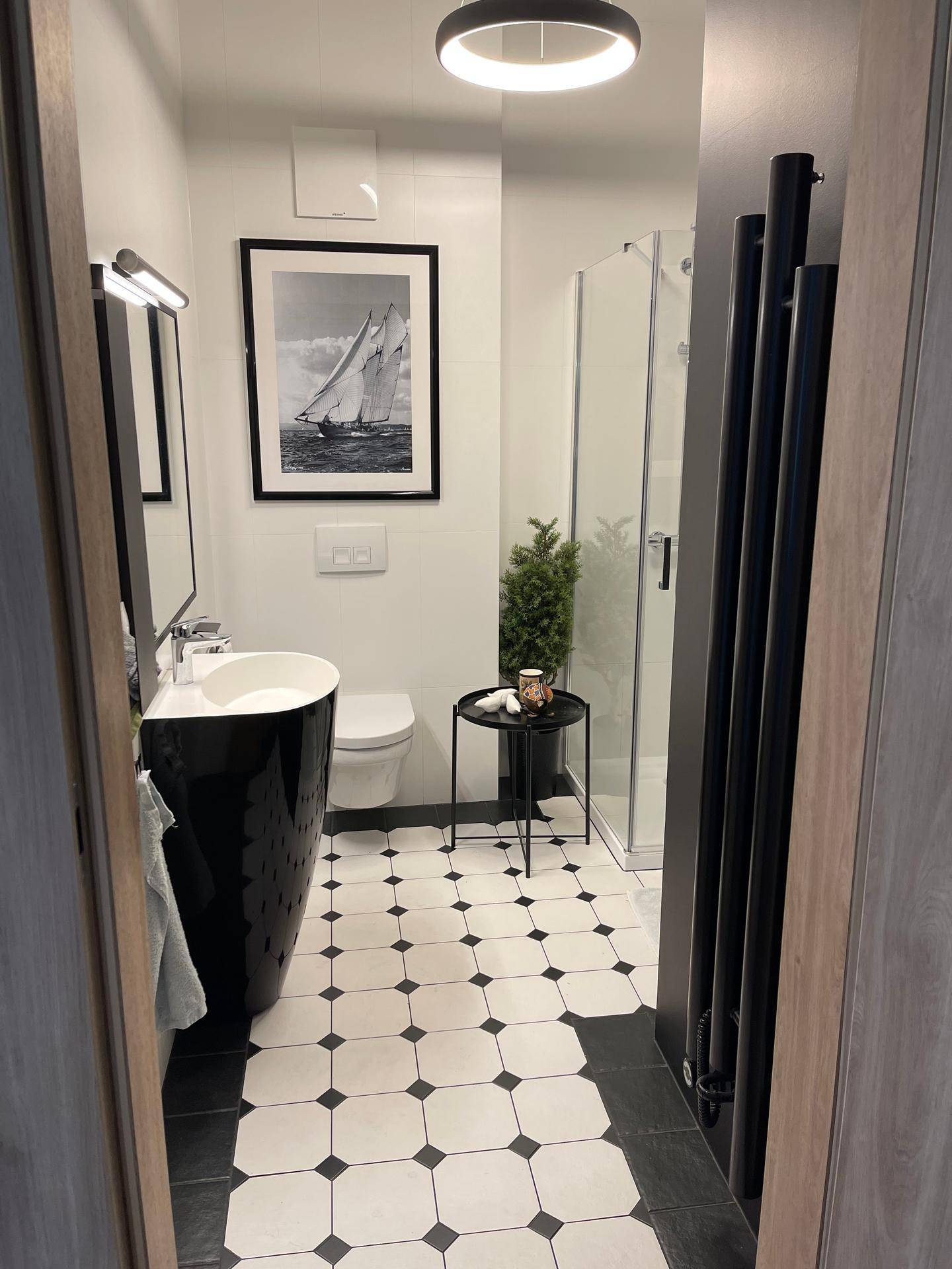 Stilvolles Badezimmer mit schwarzem Waschbecken, Duschkabine und gemustertem Fliesenboden.