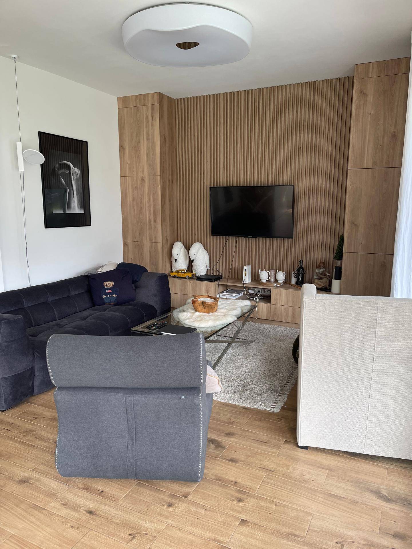 Modernes Wohnzimmer mit großem Sofa, Holzboden und stilvoller Wandverkleidung.