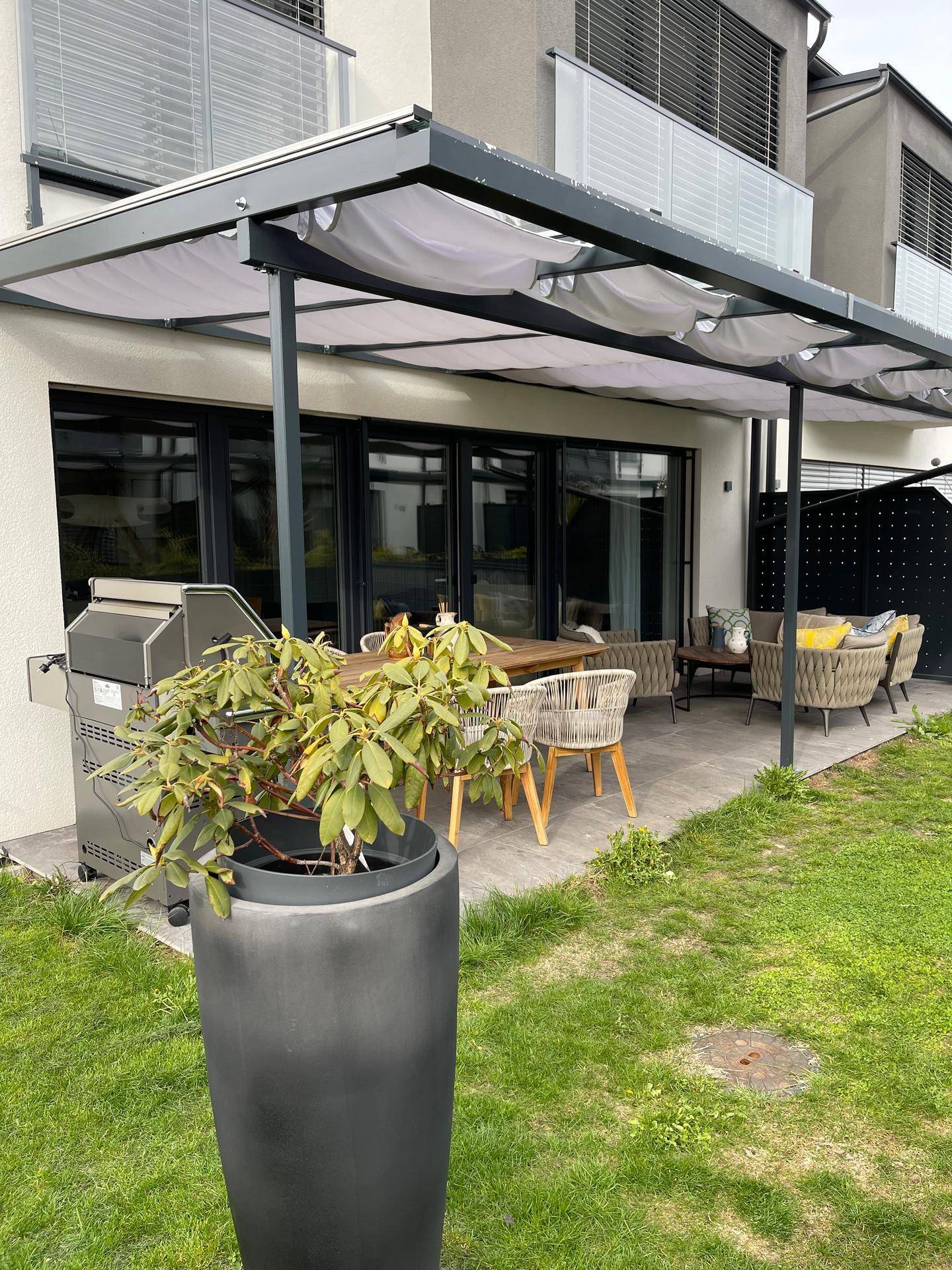 Überdachte Terrasse mit Essbereich, Lounge-Möbeln und Zugang zum grünen Garten.