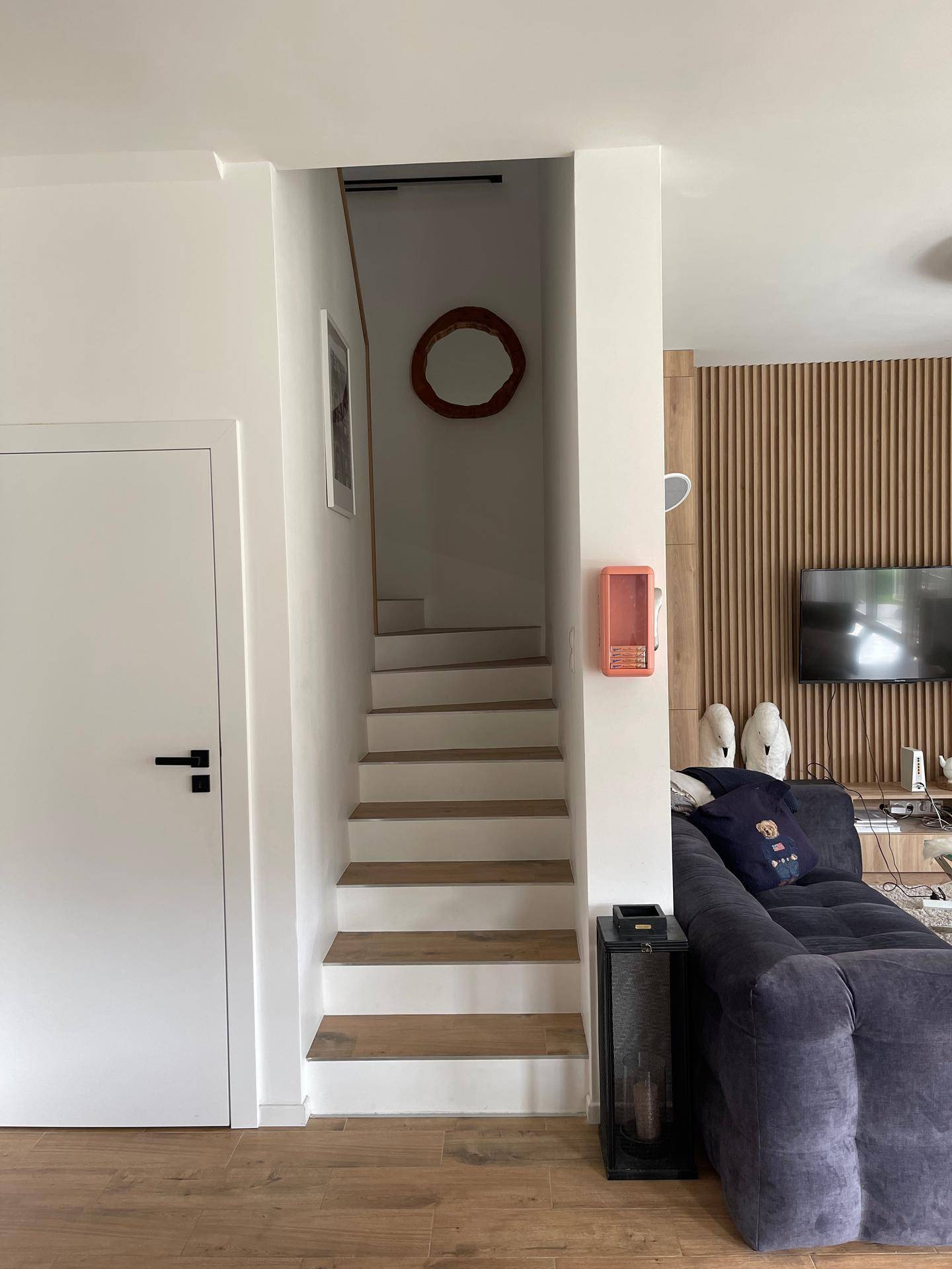 Treppenaufgang neben dem Wohnbereich mit Holzboden und moderner Wandgestaltung.