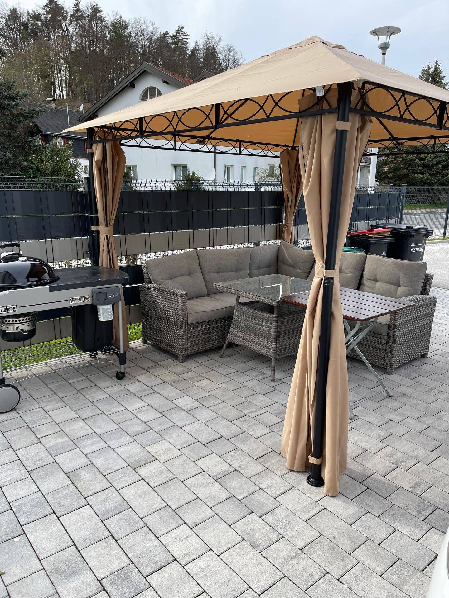 Gemütlicher Außenbereich mit Pavillon, Sitzgruppe und Grill auf gepflasterter Terrasse.