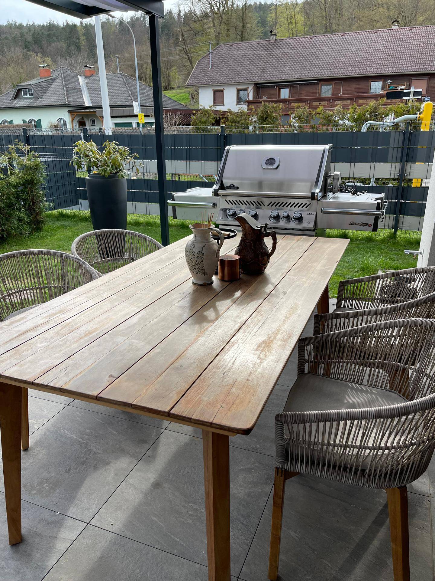 Heller Essbereich auf der Terrasse mit Holztisch und Blick auf die umliegende Landschaft.