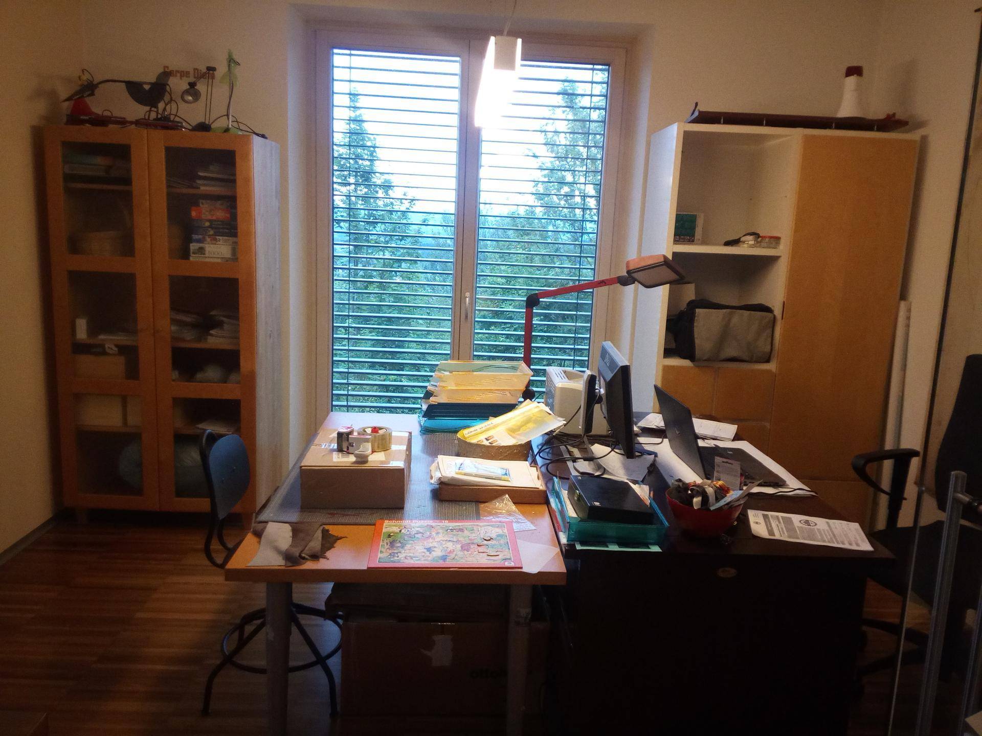 Funktionales Heimbüro mit Schreibtisch, Computer und großem Fenster mit Jalousien.