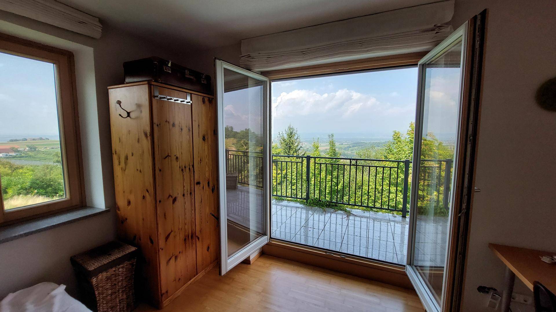 Offene Balkontür bietet einen weiten Panoramablick über die grüne Landschaft und die Umgebung.