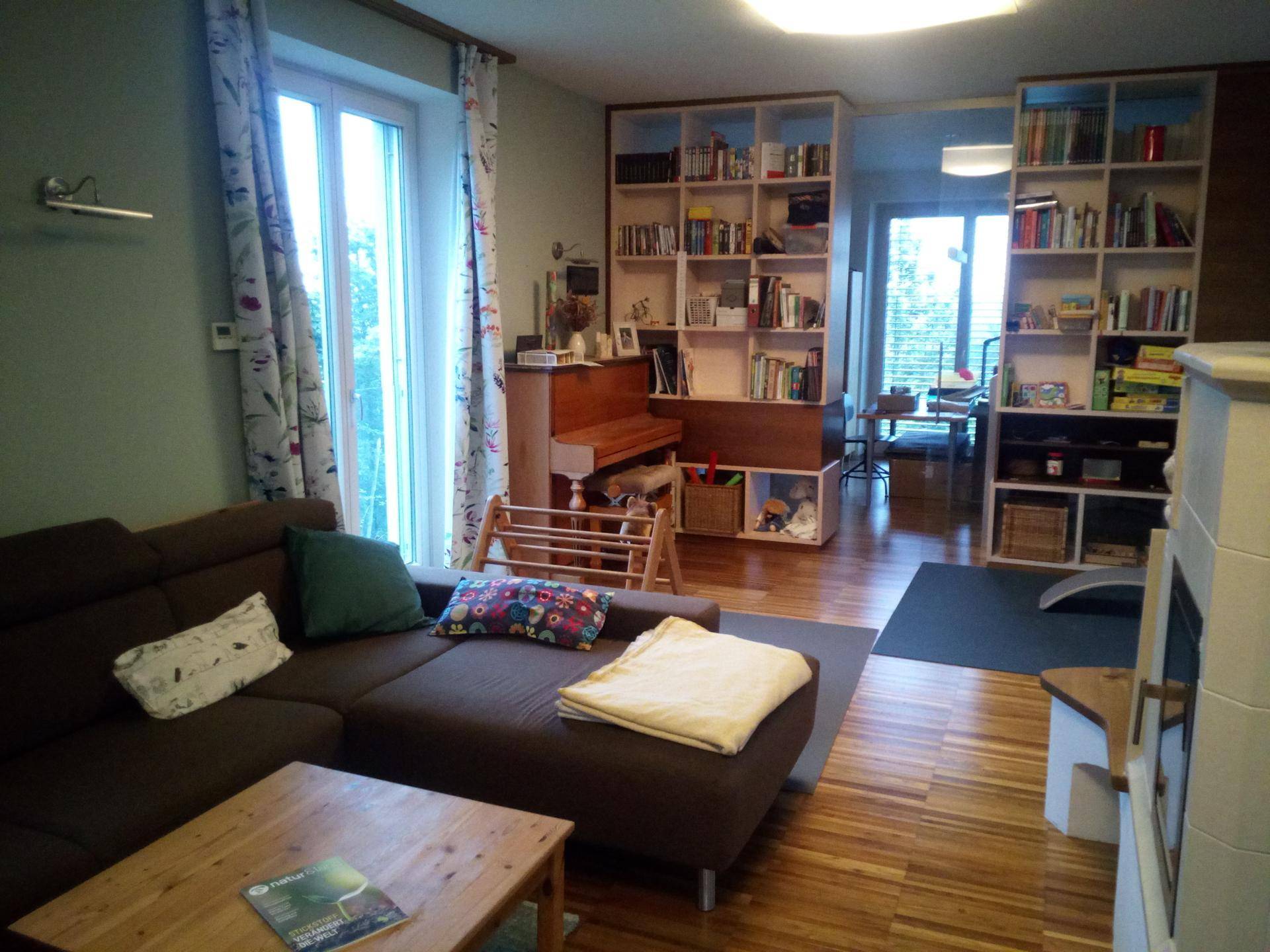 Wohnzimmer mit bequemer Couch, Bücherregalen und Blick in einen angrenzenden Raum.