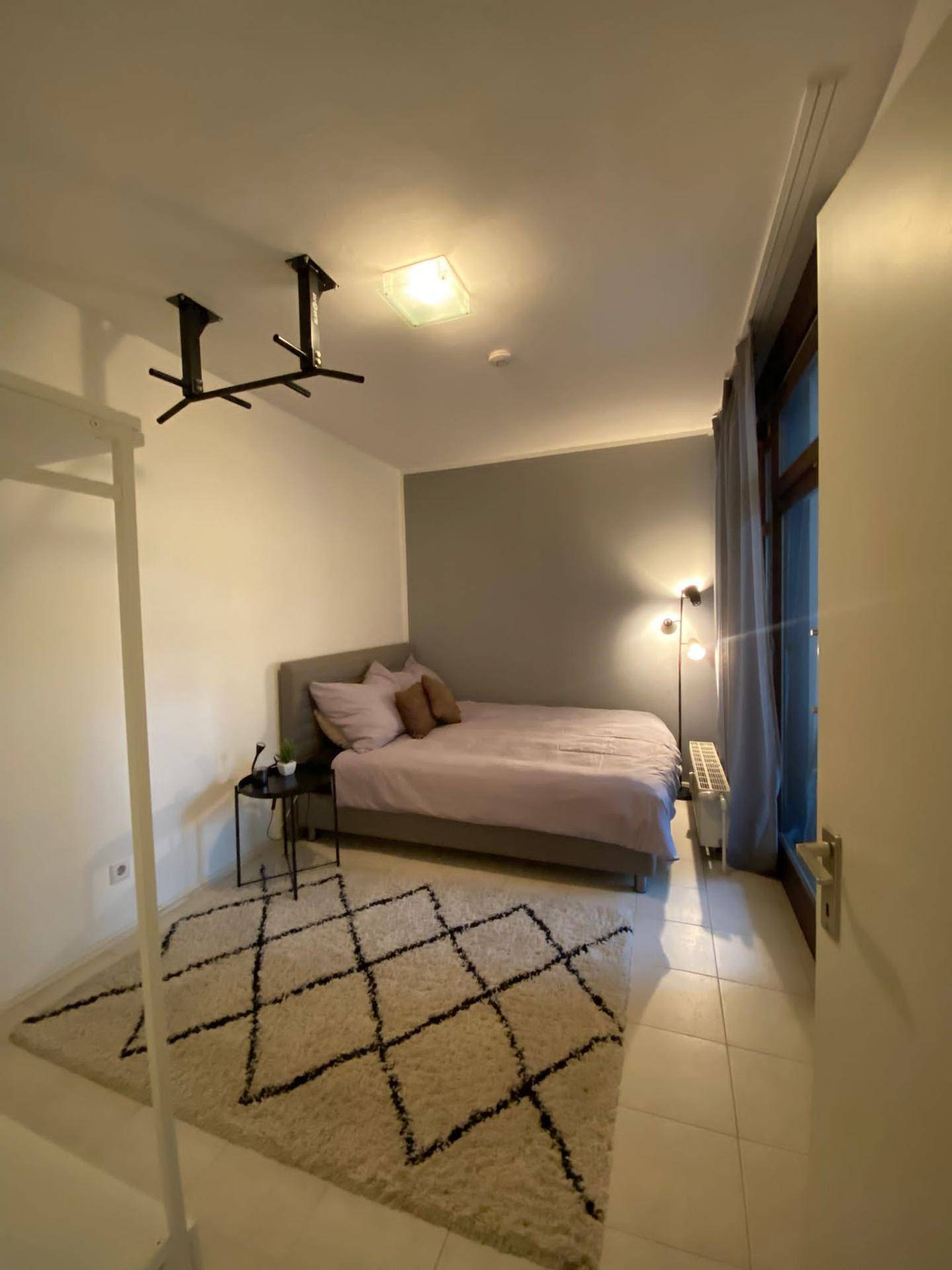 Gemütliches Schlafzimmer mit Doppelbett, Teppich und Zugang zum Balkon.